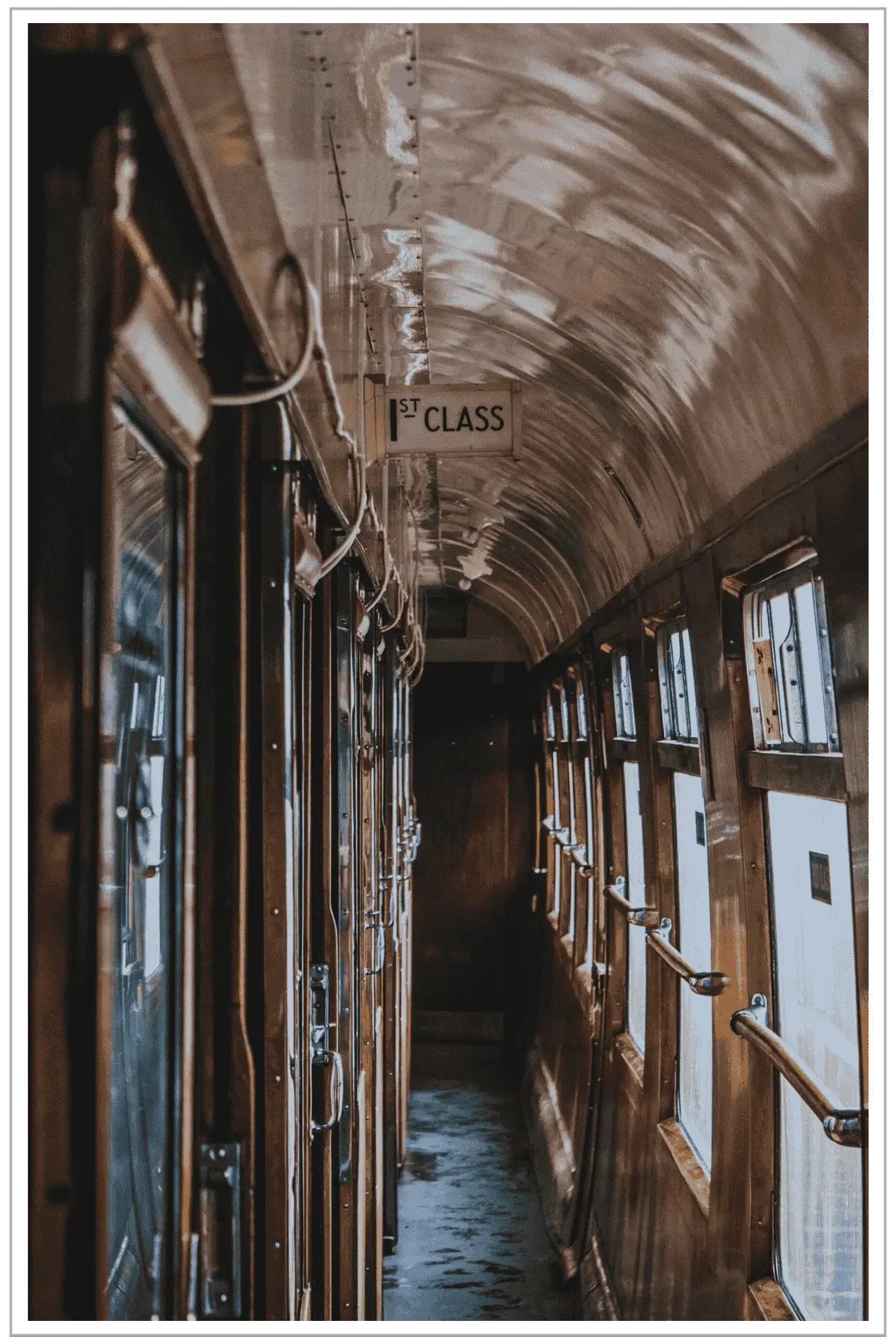Interior hallway of a luxury vintage train car at a UNESCO heritage site in the UK, familiar as the Hogwarts Express in Harry Potter. A first class sign is posted near the ceiling.