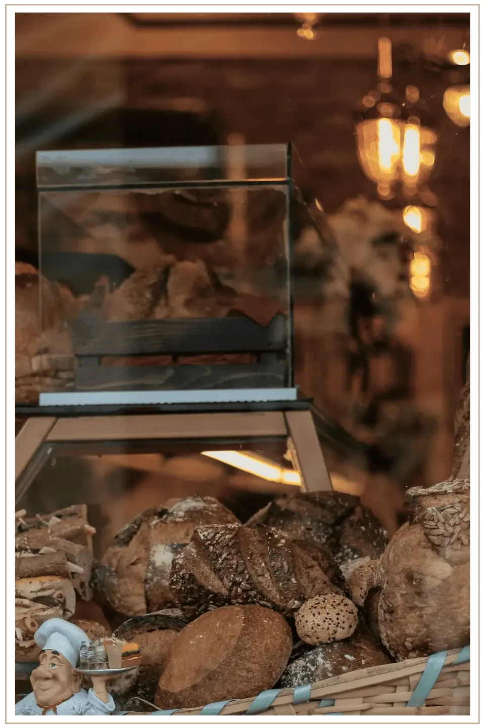 A closeup window image of a bakery in France with loaves of bread. The warm glow of the shop lighting comes from behind the window.