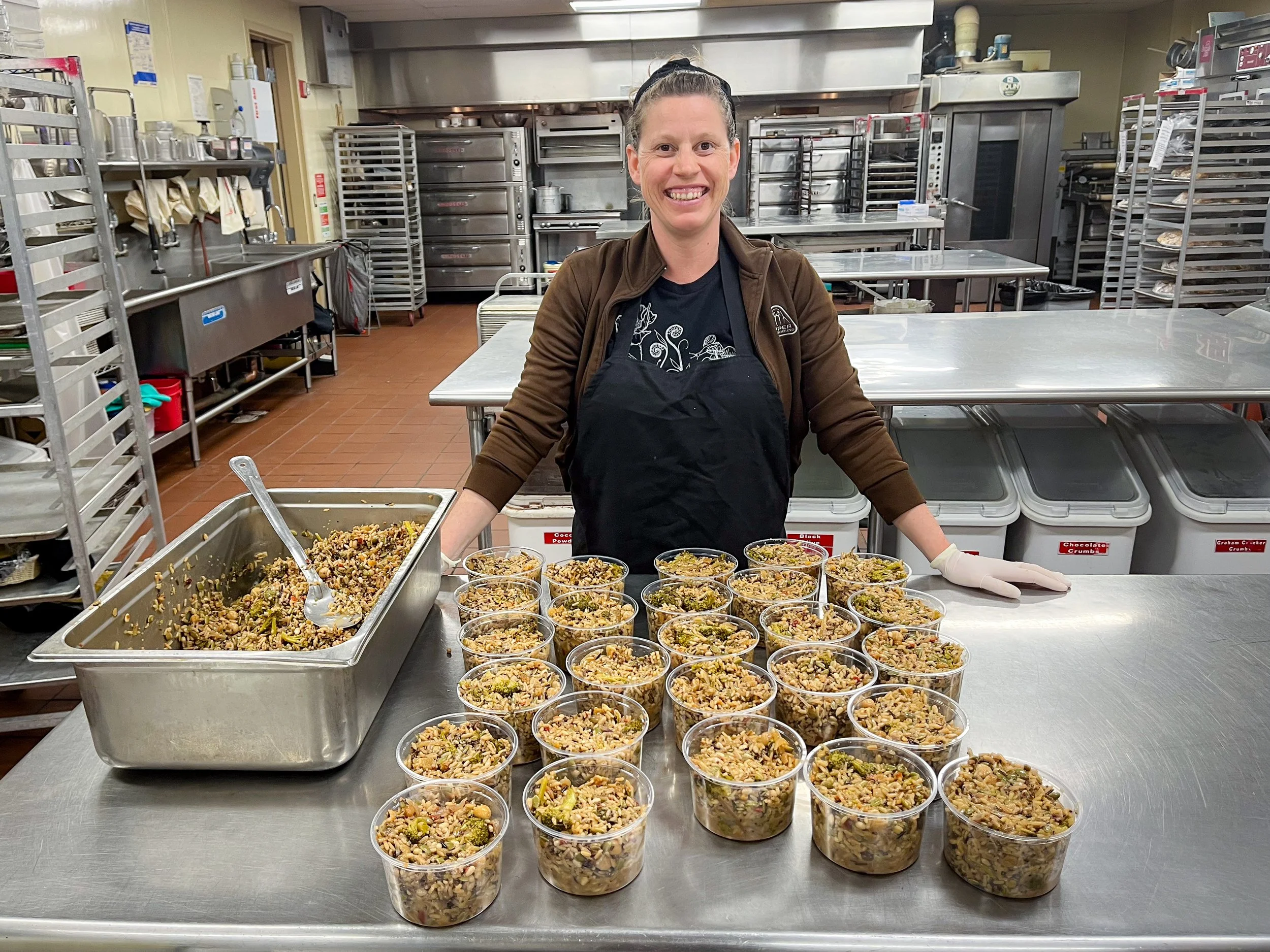 Food packager with containers of rescued meals in CAFE Food Rescue kitchen
