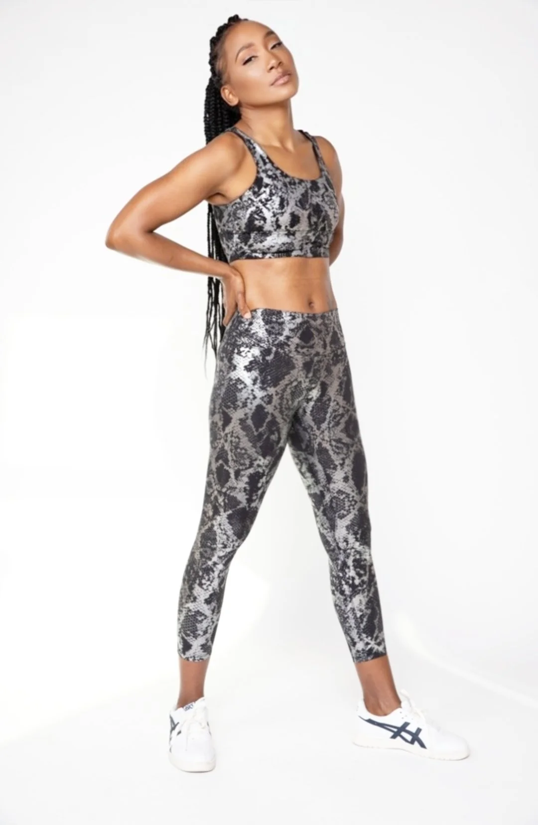 Woman in snake print athletic wear posing with her hand on her back and looking confidently at the camera.