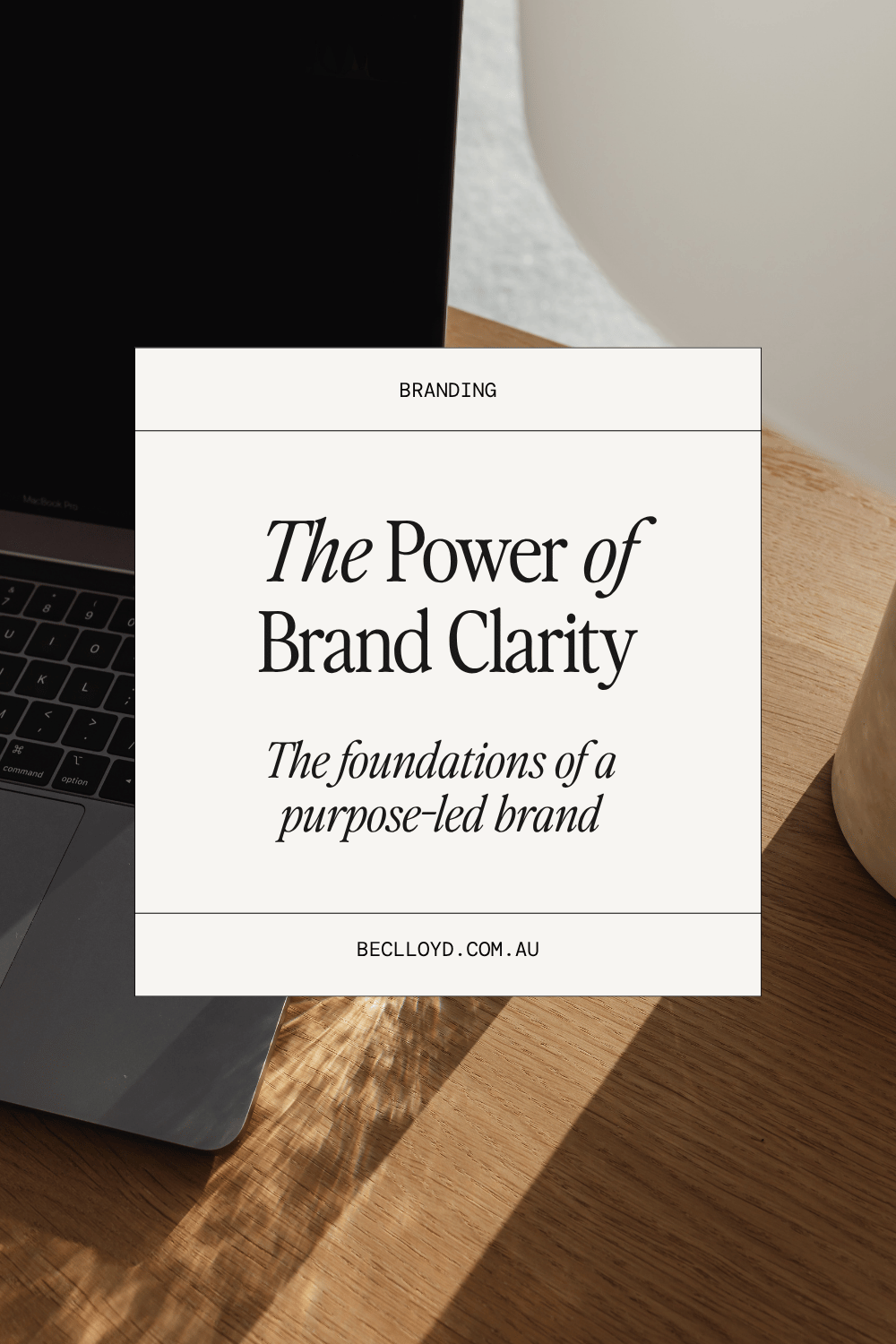 'The Power of Brand Clarity' text overlay in a white box set on an image of a laptop on a wooden text.