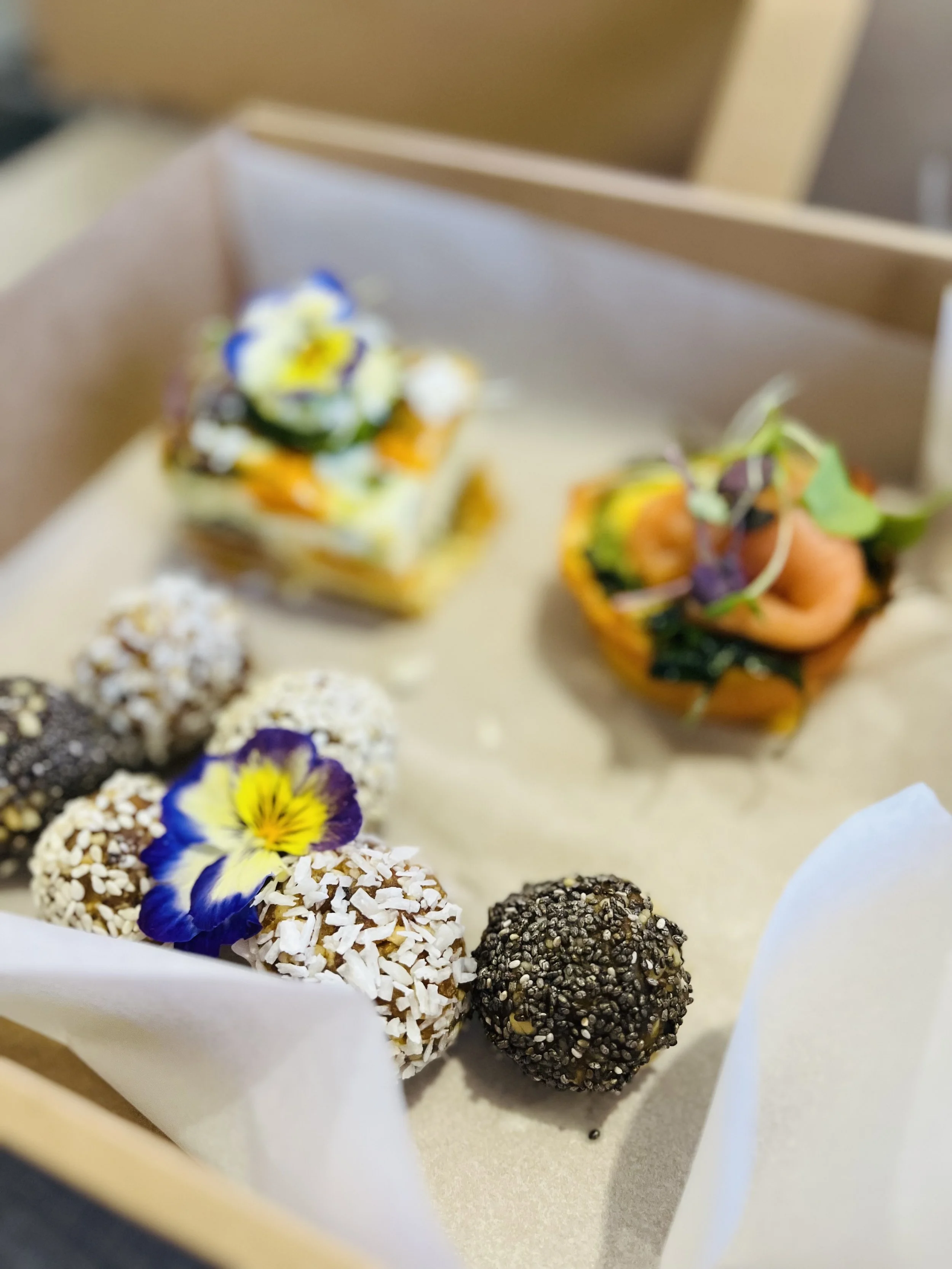 Assorted gourmet appetizers and desserts with edible flowers on a tray.