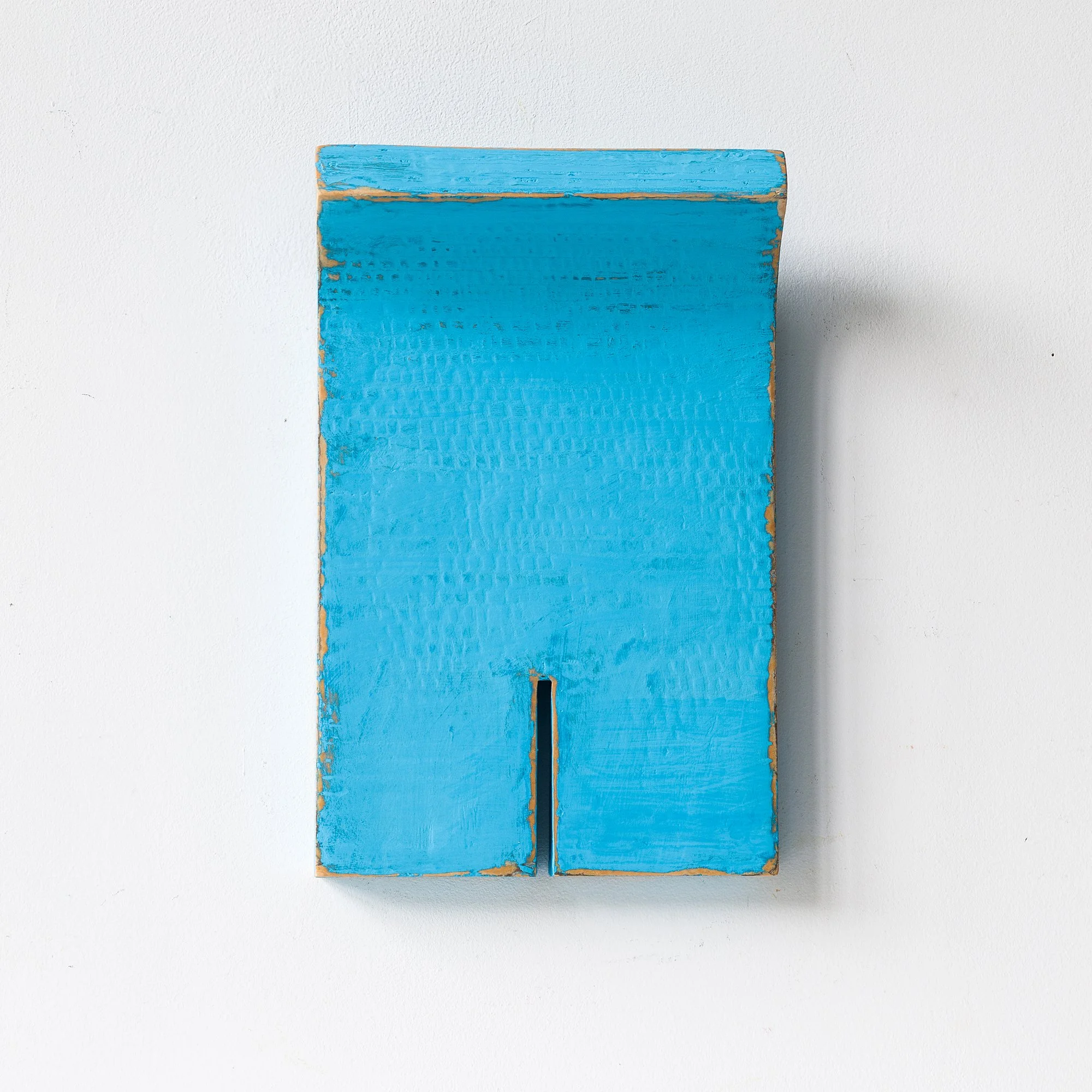 Blue rectangular artwork with a small notch, mounted on a white wall.