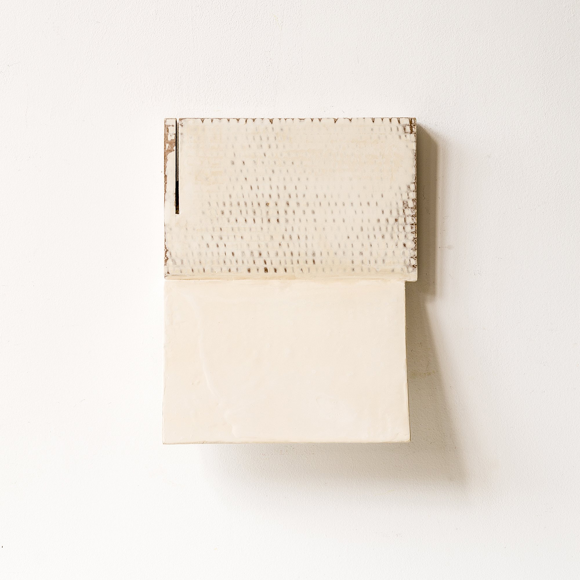 SOLD

This minimalist wall sculpture is a small, original artwork constructed from reclaimed cardboard. The piece features a textured upper surface and a folded lower plane, creating quiet dimensionality and soft shadow interaction. Its neutral off-w