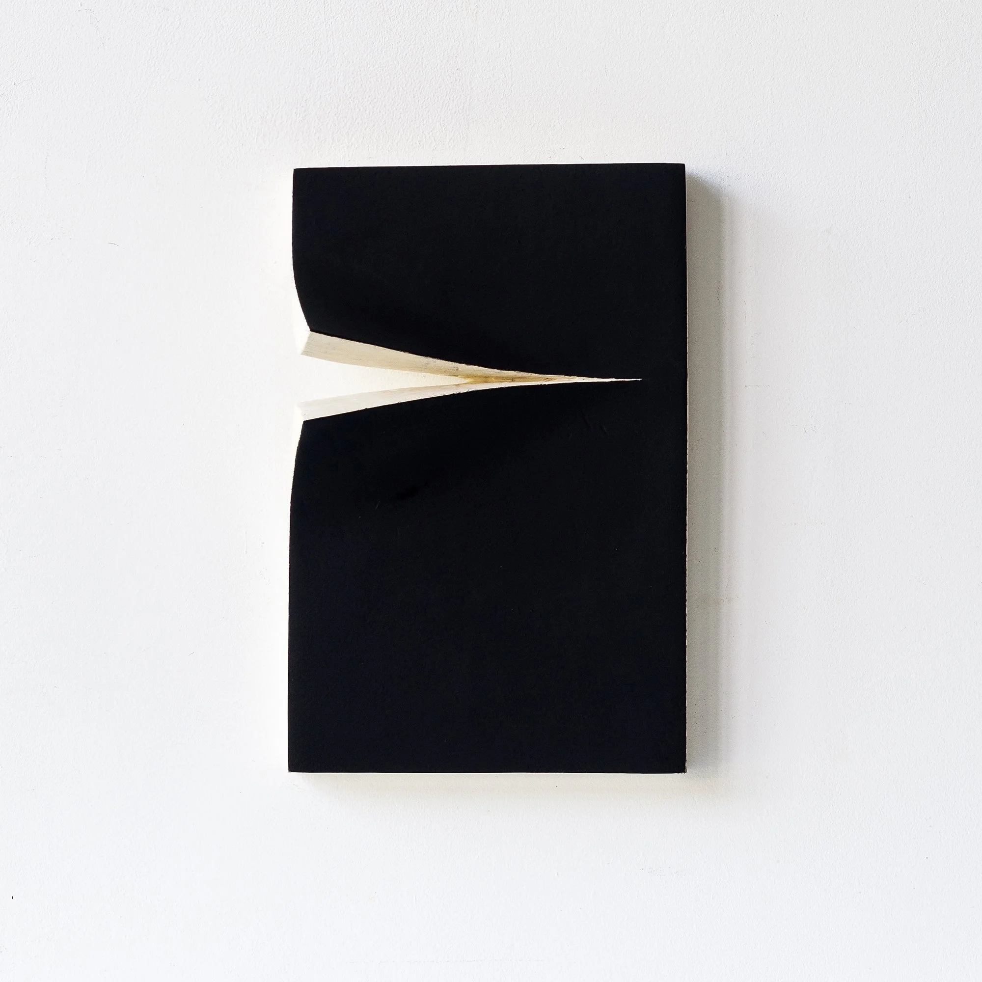 Original 3D wall piece constructed from hand-cut cardboard painted matte black. A precise horizontal cut and gently lifted flaps reveal the raw edge beneath, forming a sculptural gesture that plays with depth and light. This work explores absence, su