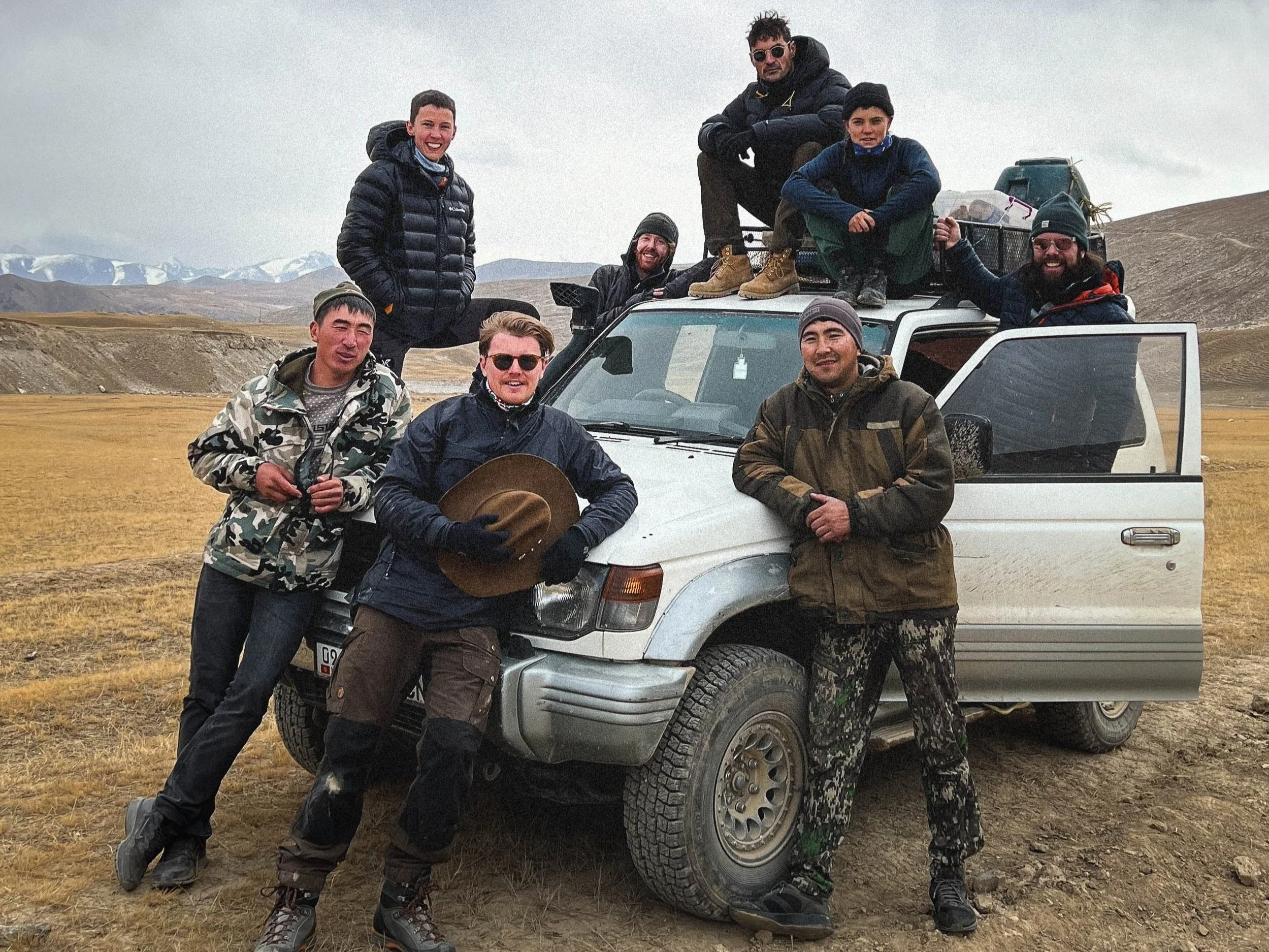 Group of people standing next to a jeep in Kyrgyzstan in search of snow leopards