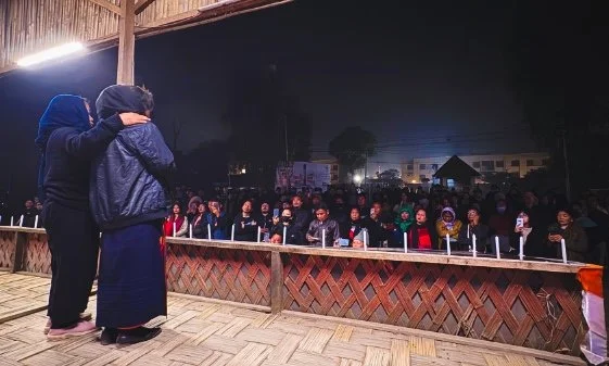 Two female relatives of the victim face a crowd with candles.