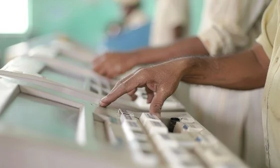 Hands casting votes through machines.