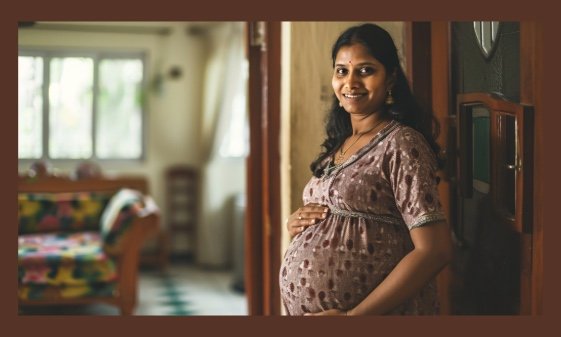 A pregnant woman showing her stomach in her home.