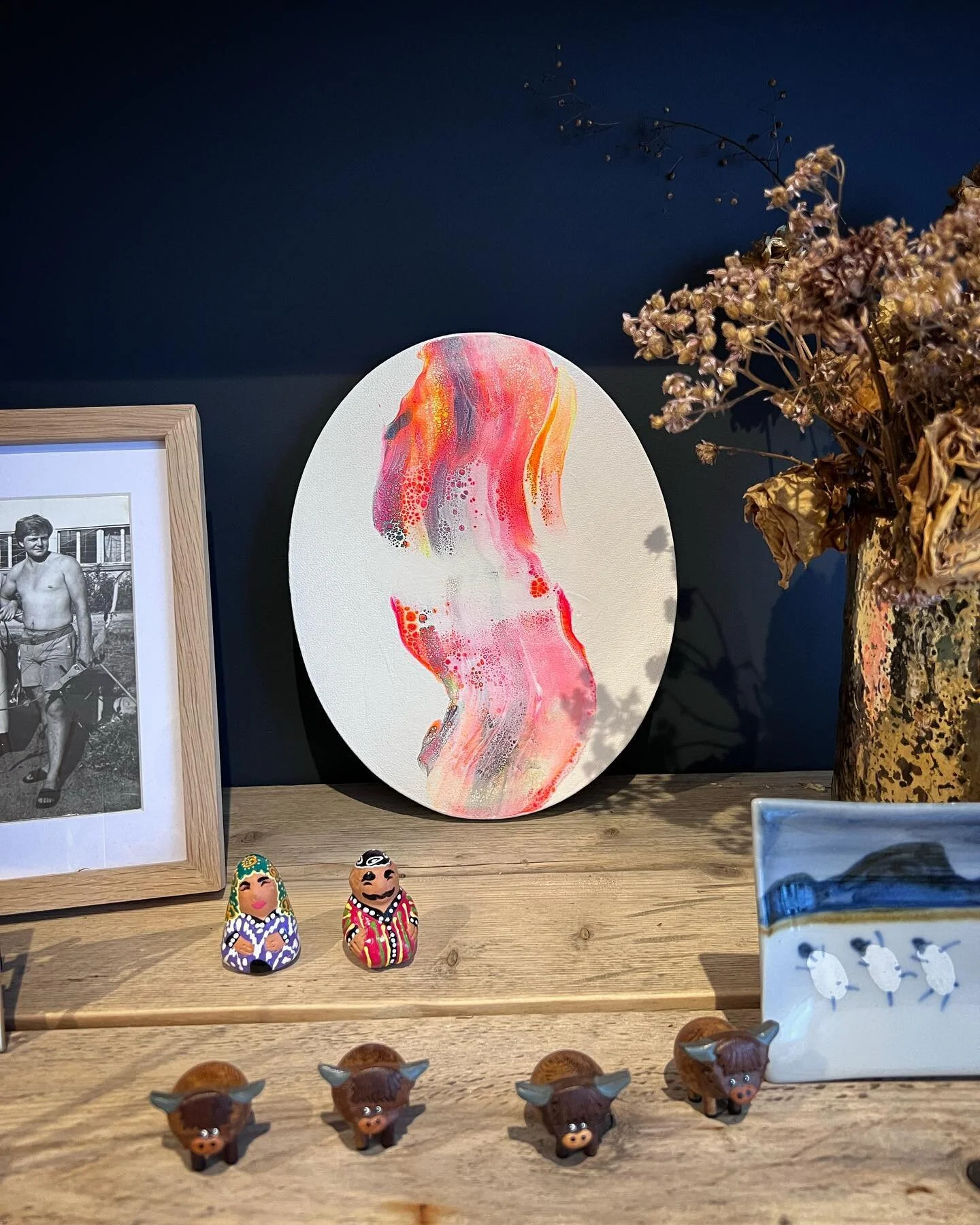 Oval painting looking fab against our dark wall, adding a splash of colour. It&rsquo;s almost like a having a cozy fire in the room. #interiorcolours #cozyinterior #shelfstyling #artforsaleuk #glasgowartist #glasgowart #fire #cozyrooms