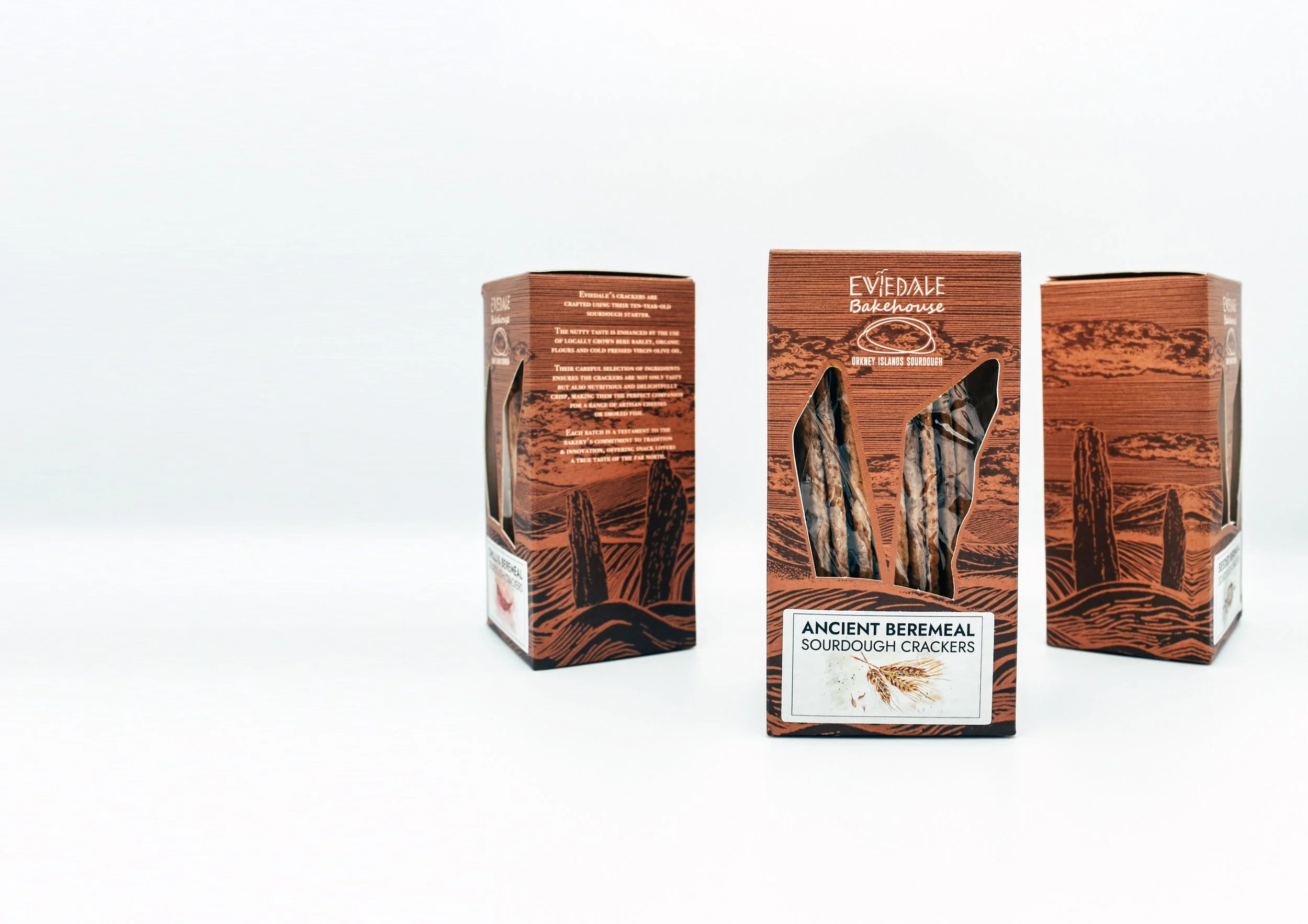 Three boxes of Ancient Bermeal sourdough crackers with mountain and wheat graphics on a white background.