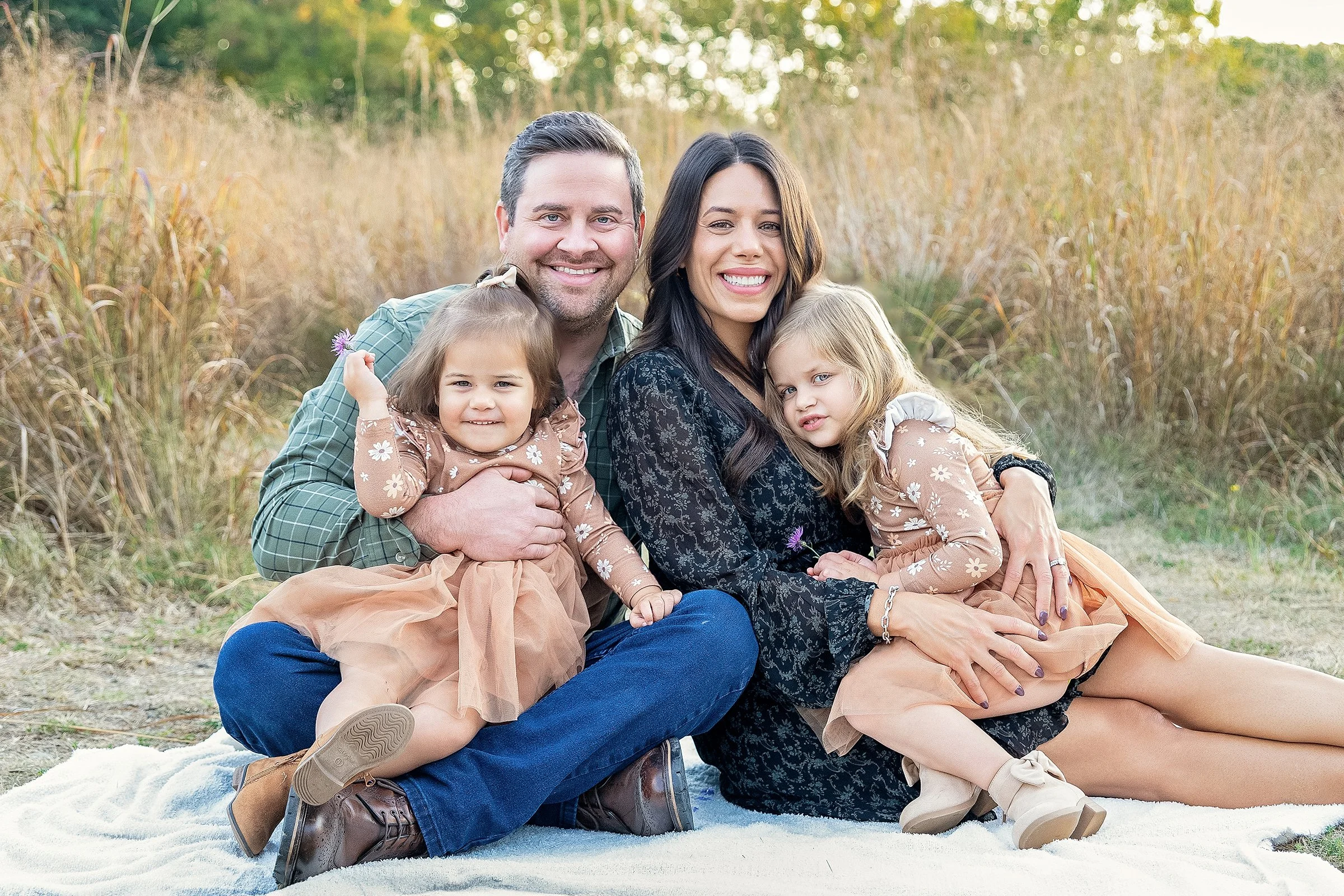 Family portrait with parents and two daughters sitting together during an outdoor family photography session in Rochester Hills photographed by El & Em Photography