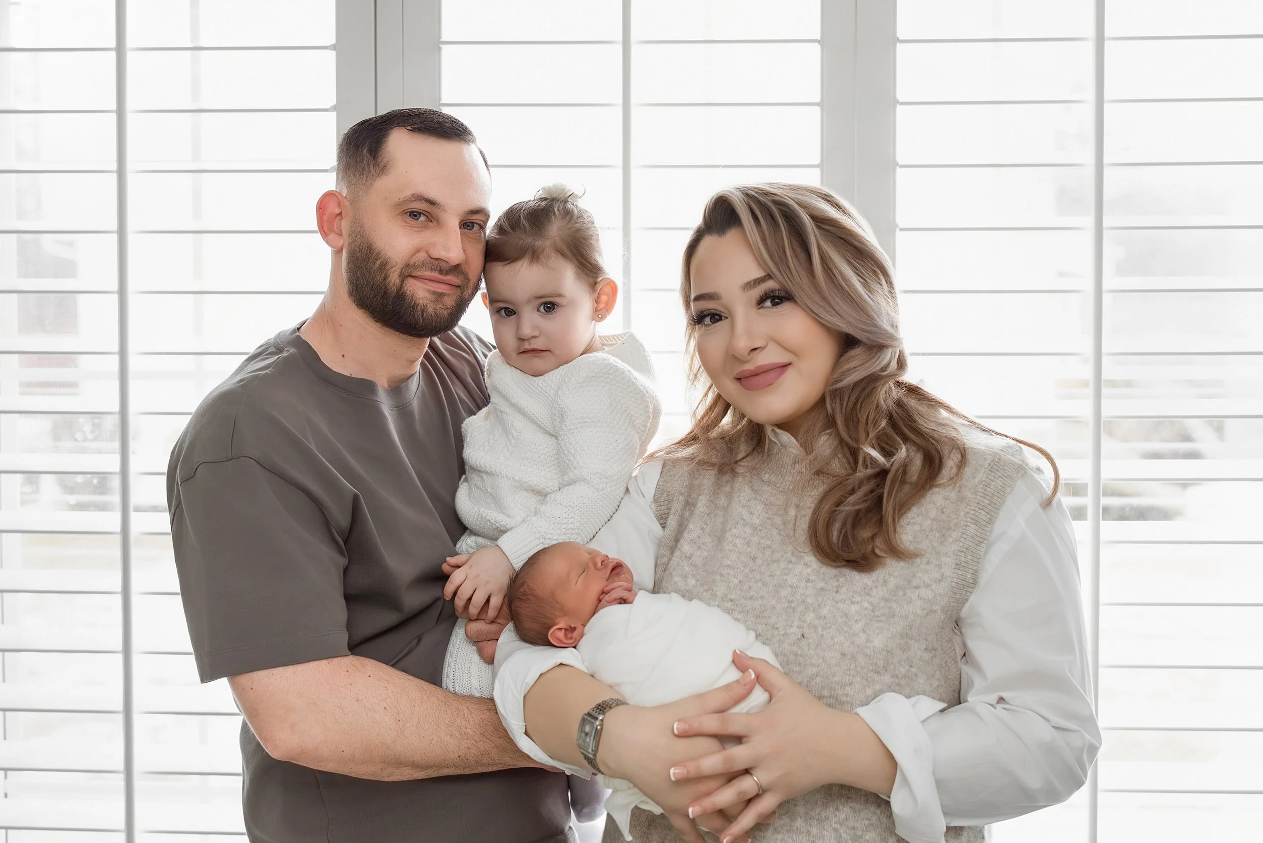 Family portrait with parents, toddler sibling, and newborn baby during a Rochester Hills newborn photography session.