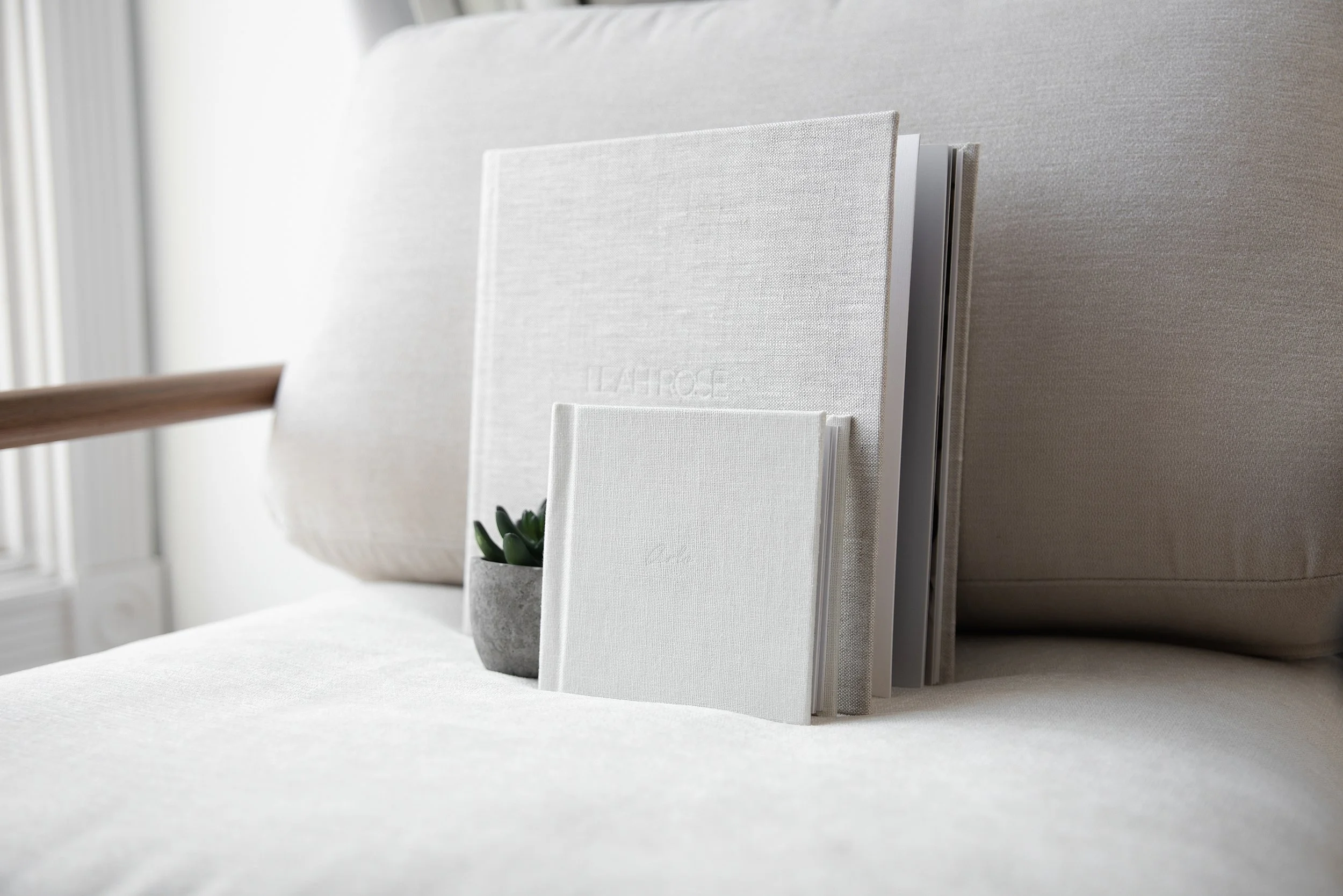 Heirloom linen photo album displayed on neutral sofa at Rochester Hills Michigan newborn and family photography studio