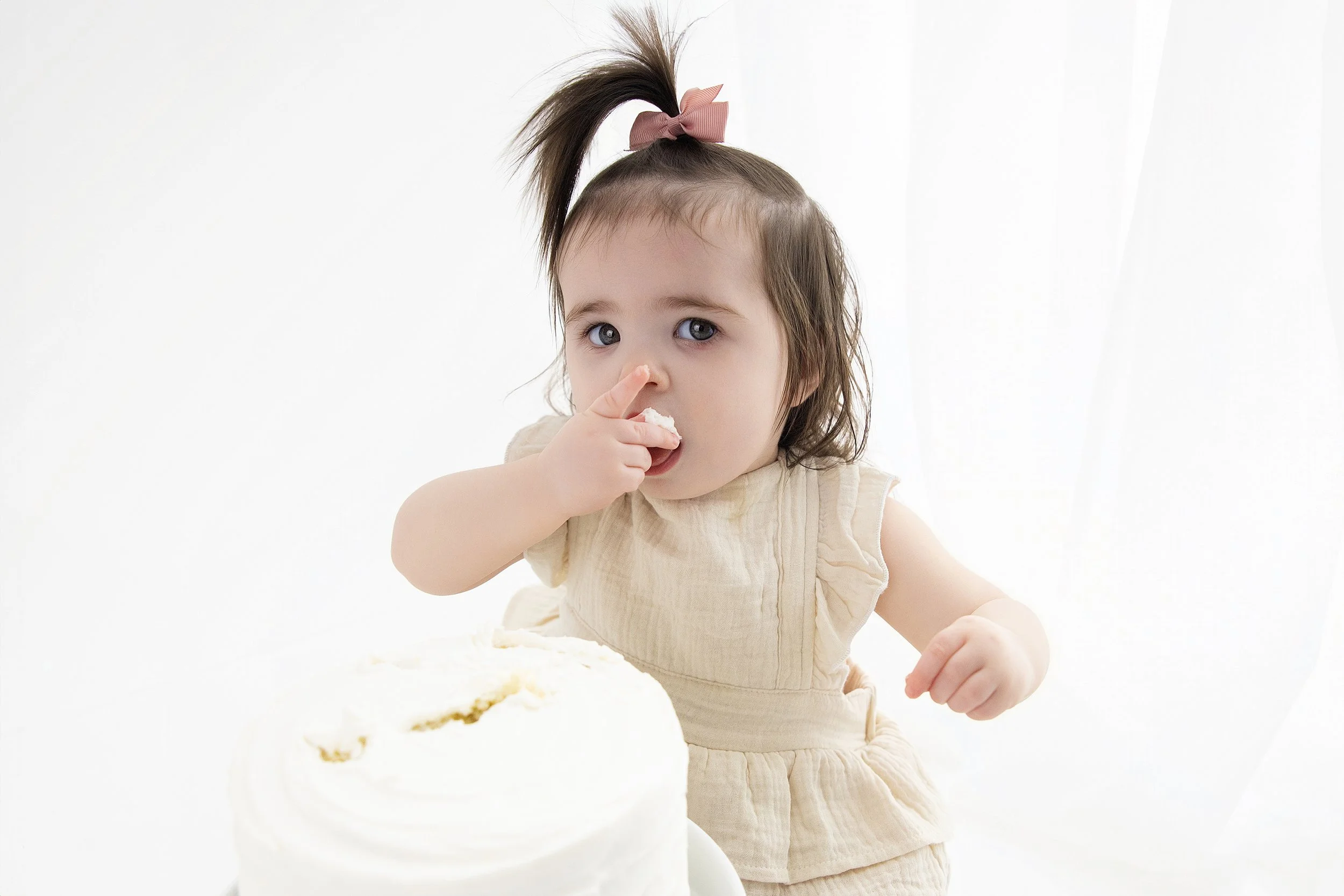 Baby girl eating cake during first birthday cake smash session | Rochester Hills cake smash photographer | El & Em Photography