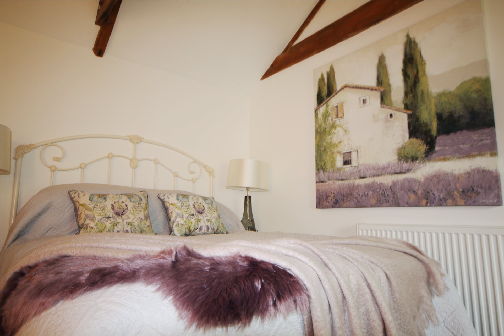A picture of a house with extensive lavender is reflected in the bedroom throws and cushions.