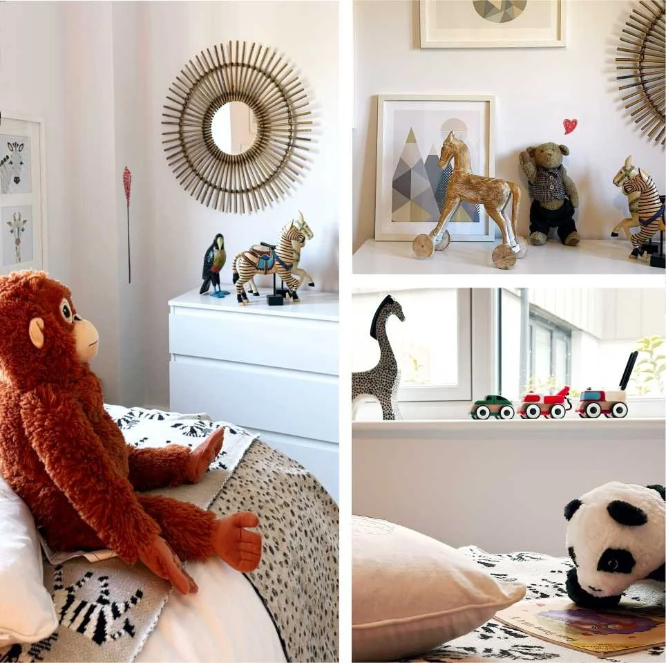 A toy monkey is surrounded by traditional toys and decorations.  There is a panda giraffe wooden vehicles and wooden horse, zebra and merry-go-round horse