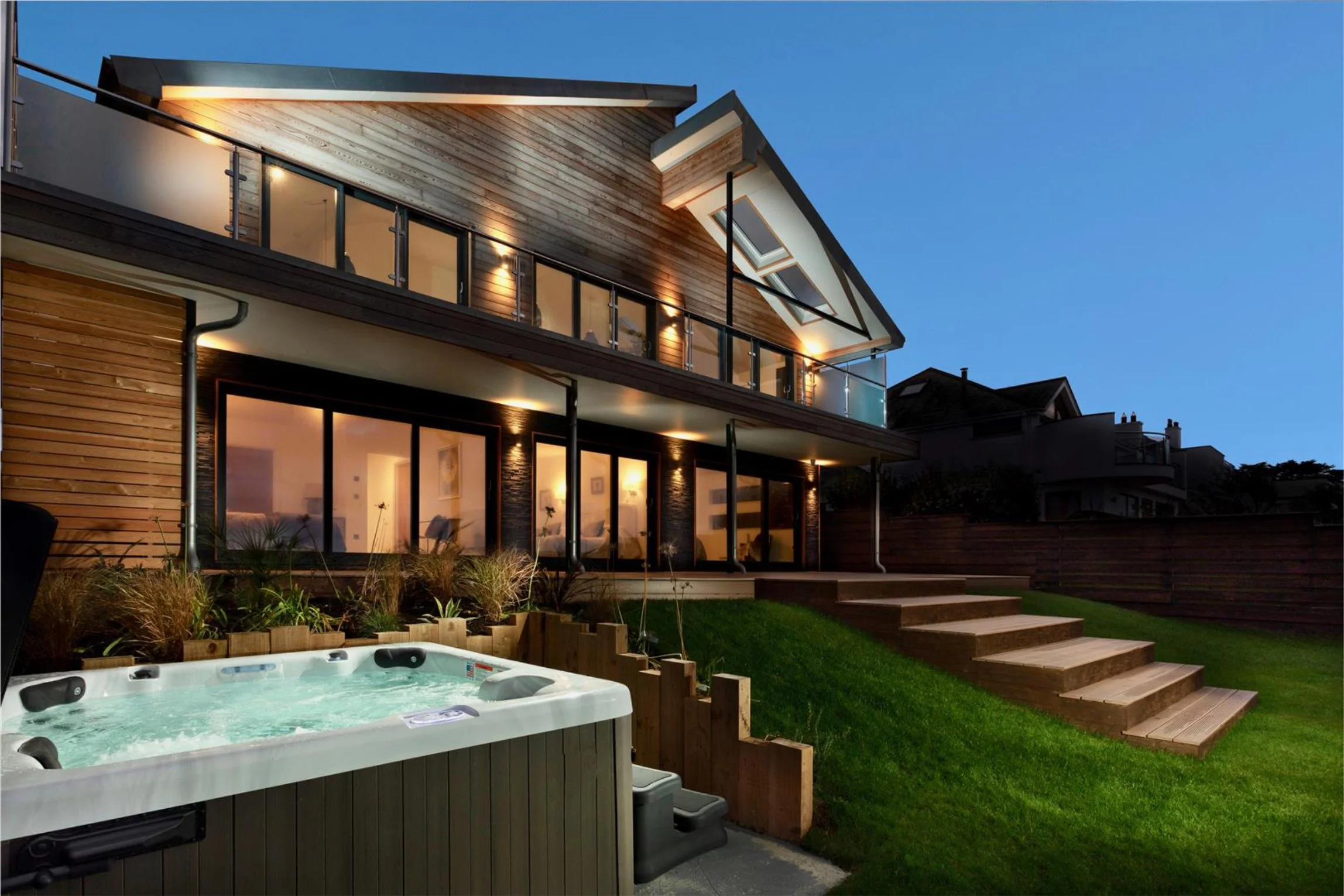 A jacuzzi bath is in a lawned garden with a modern build home