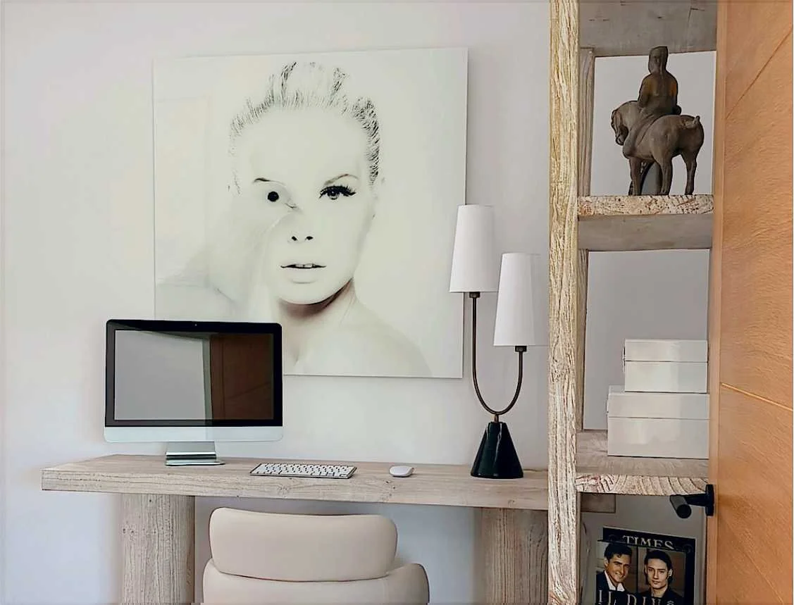 A home office with solid wood desk and white leather chair.  The stylised artwork is a photograph of a ladies face with a dove and has retro vibes