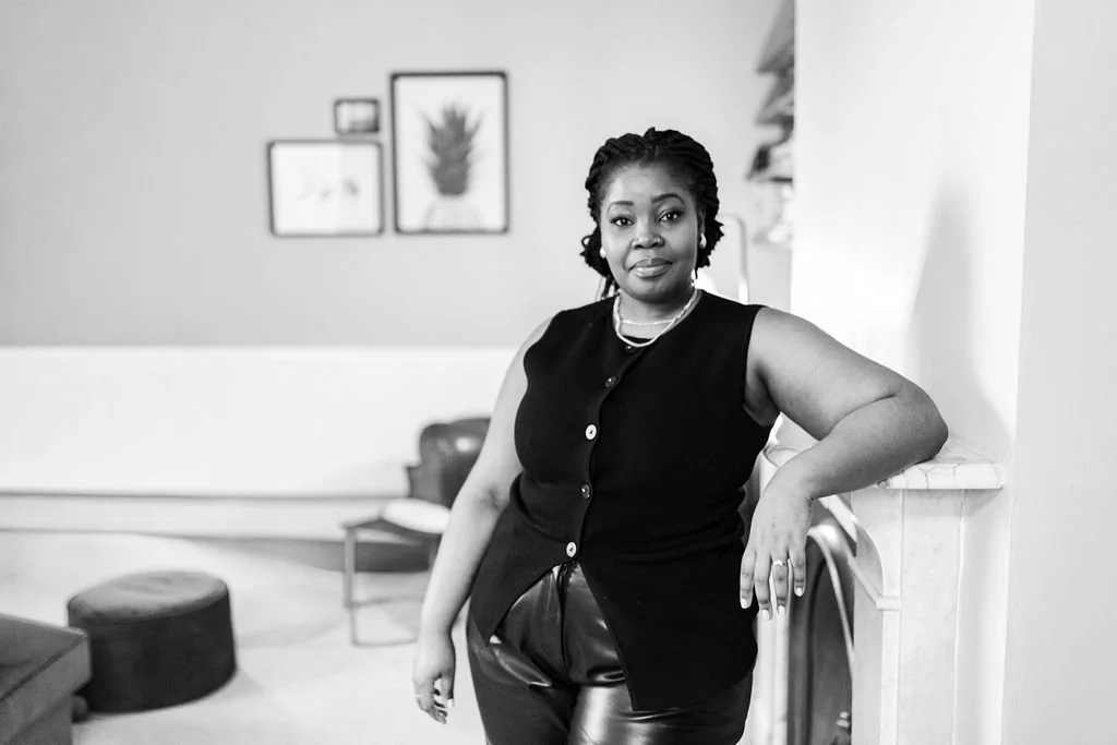 An image of a black professional women standing by a fireplace