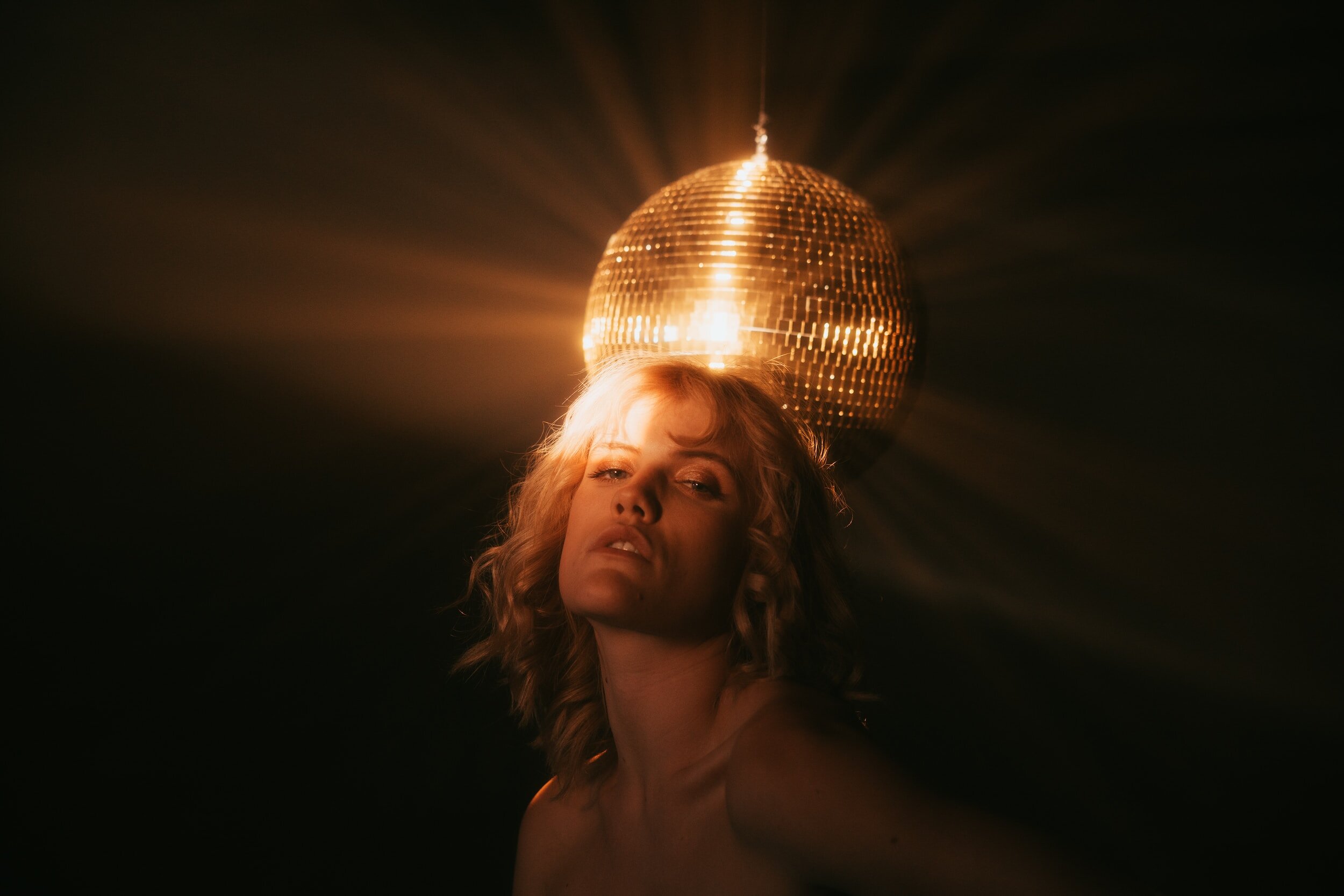 A woman posing in front of a disco ball