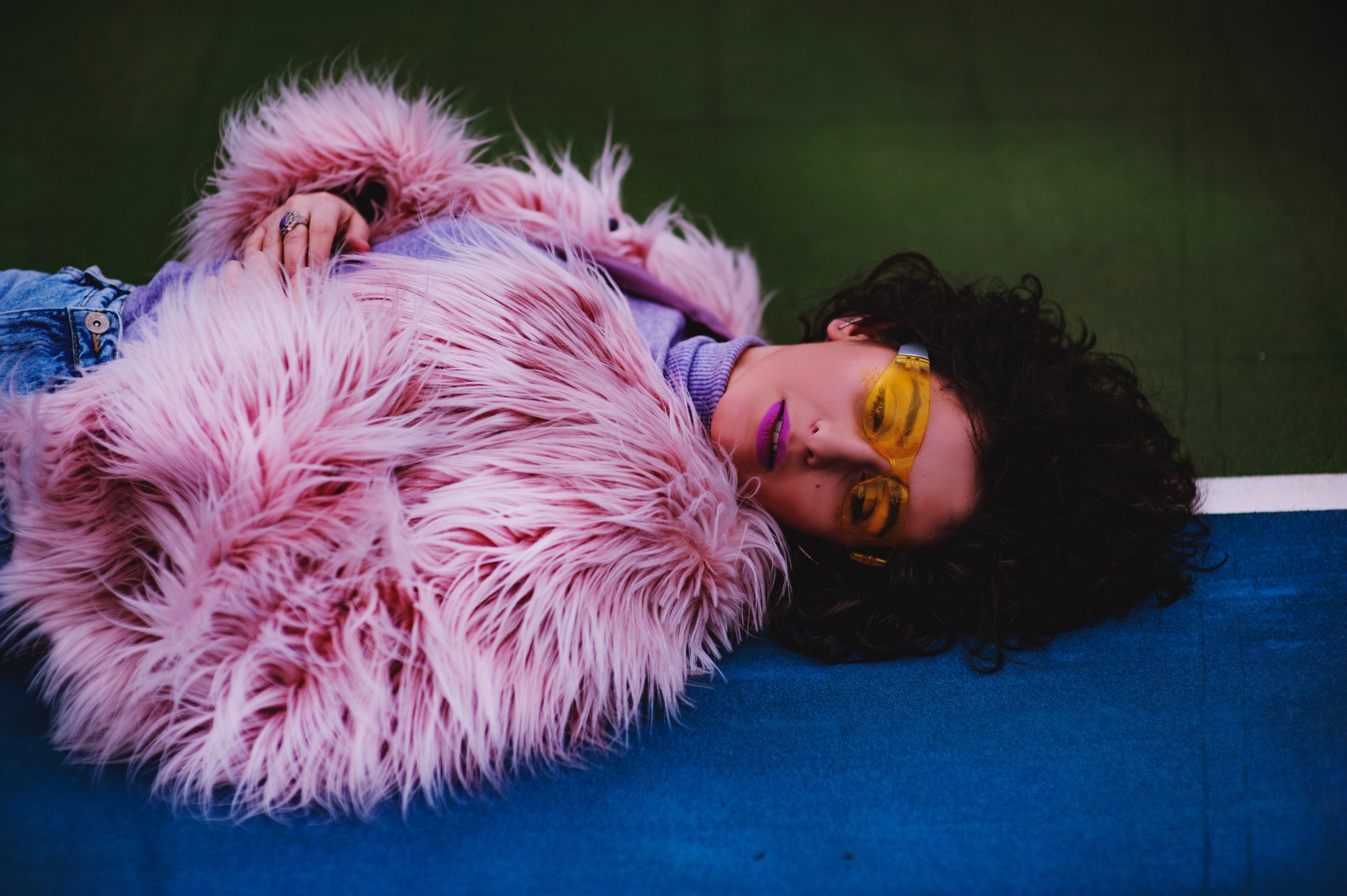 A fashionable woman in a furry pink coat with yellow sunglasses