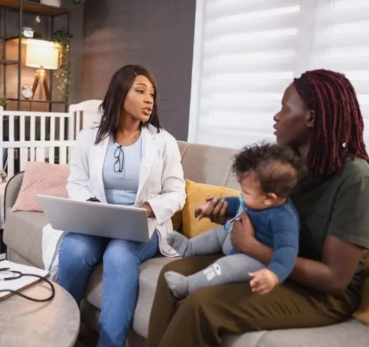African American nurse or doctor talking with mother who is holding  baby.