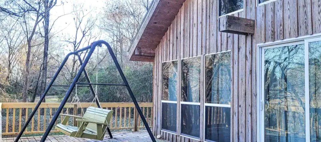 linger longer 2 front porch with swing and large windows on the front of the cabin to overlook the river
