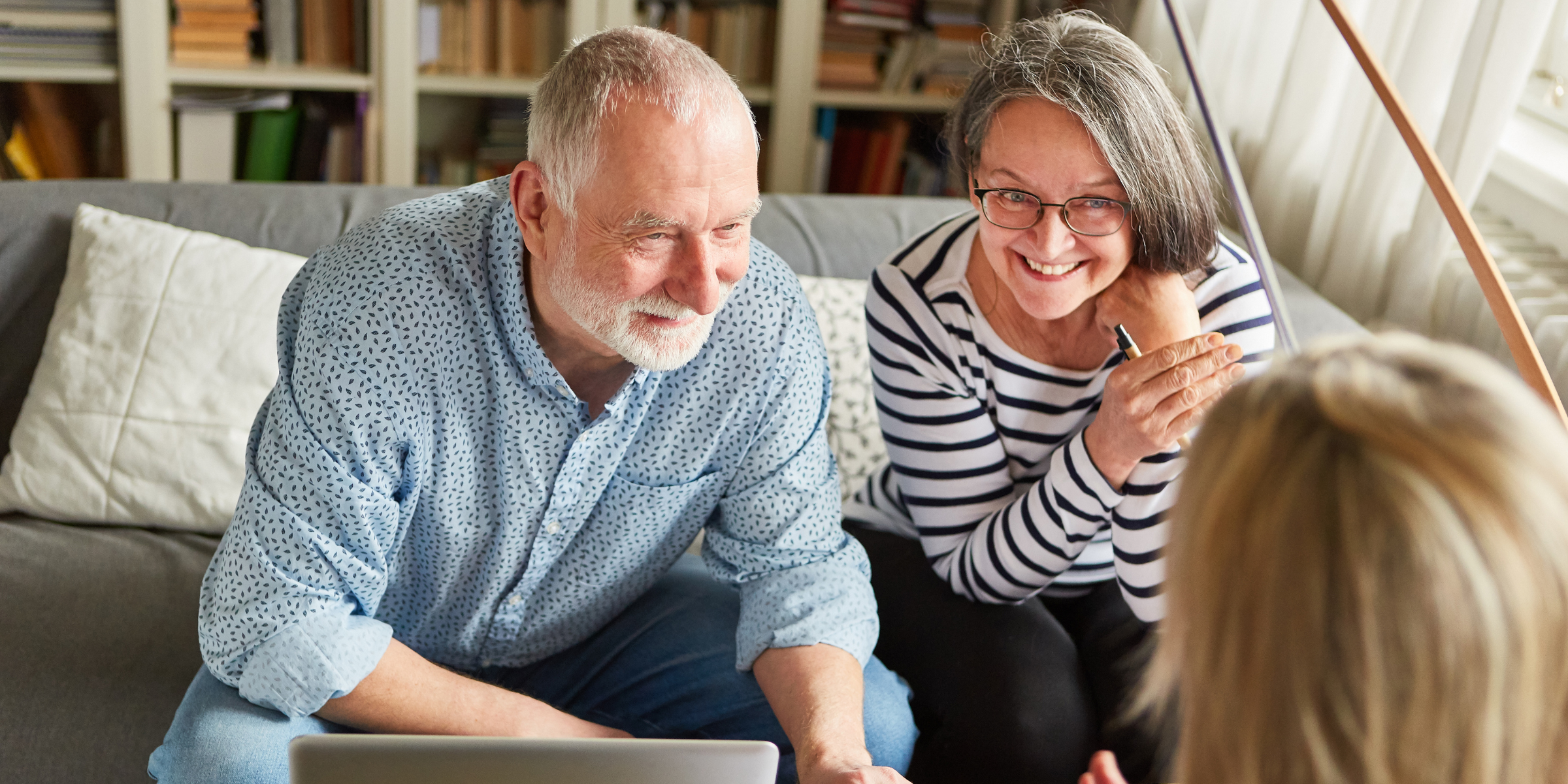 An older couple sitting on a couch smiling and talking with an advisor over a laptop.