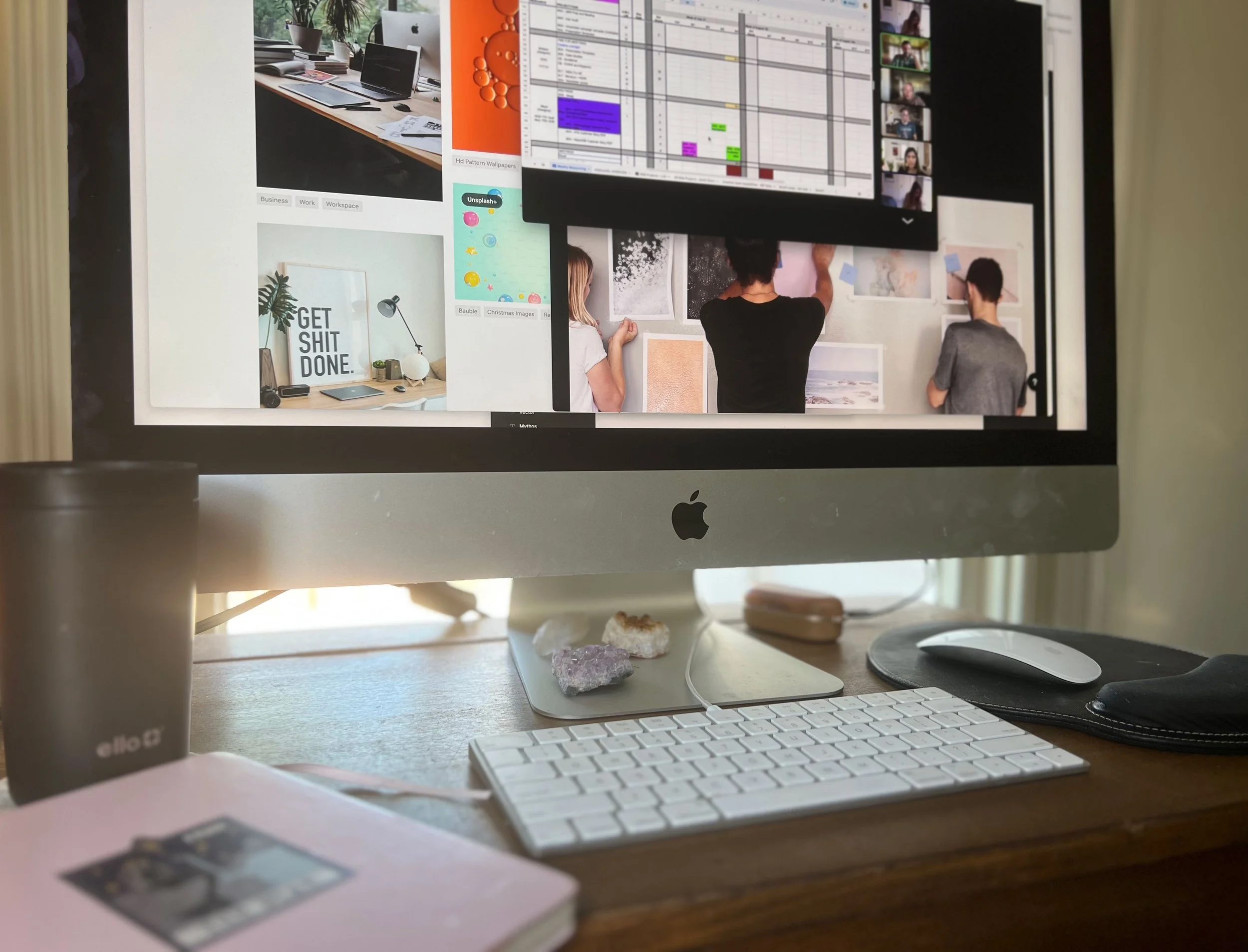 Designers office desk with Mac, keyboard, mouse, sketchbook, and coffee mug