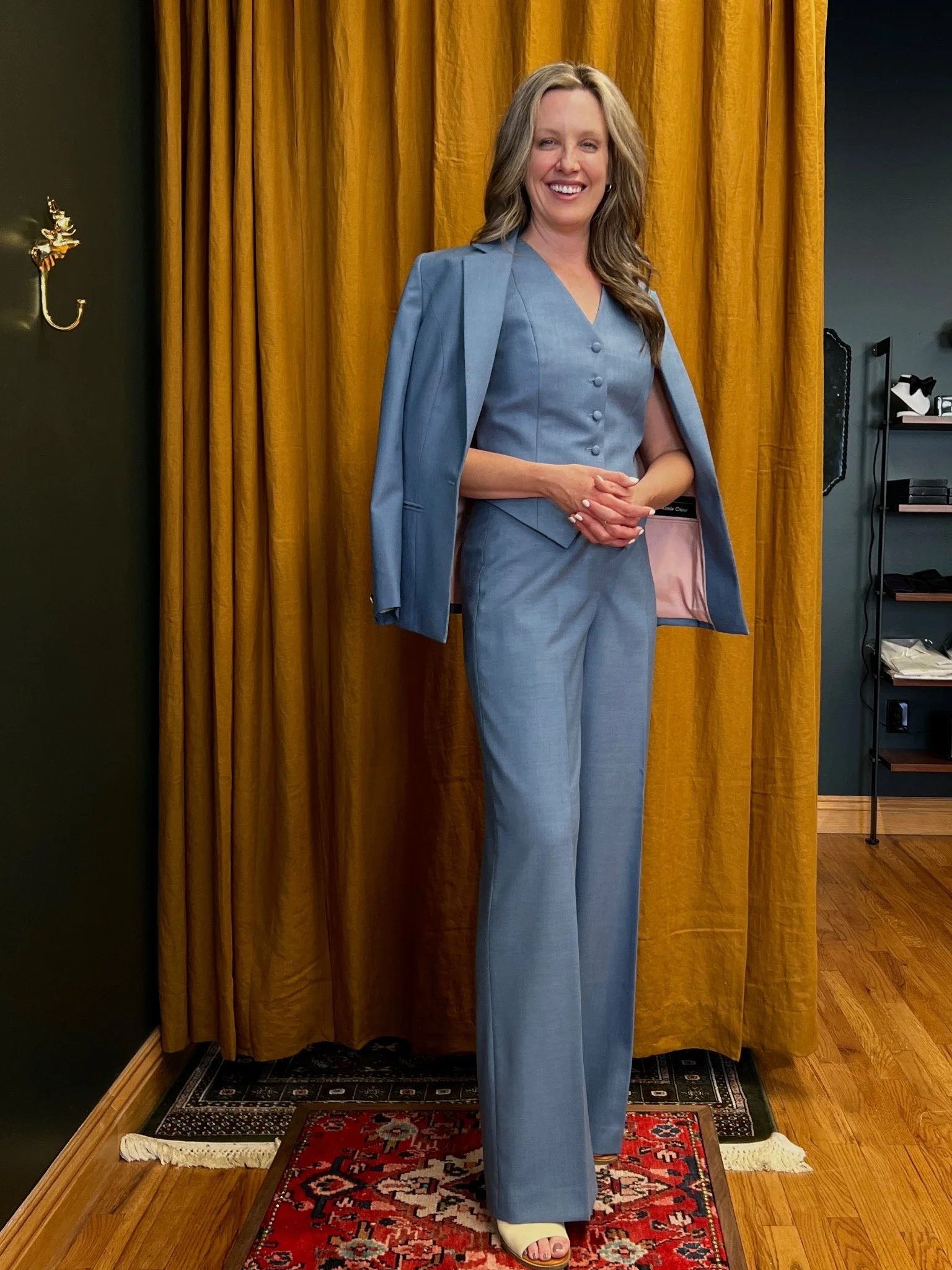Woman wearing a blue three-piece suit with a shaped waistcoat, wide-leg trousers, and jacket draped over her shoulders.