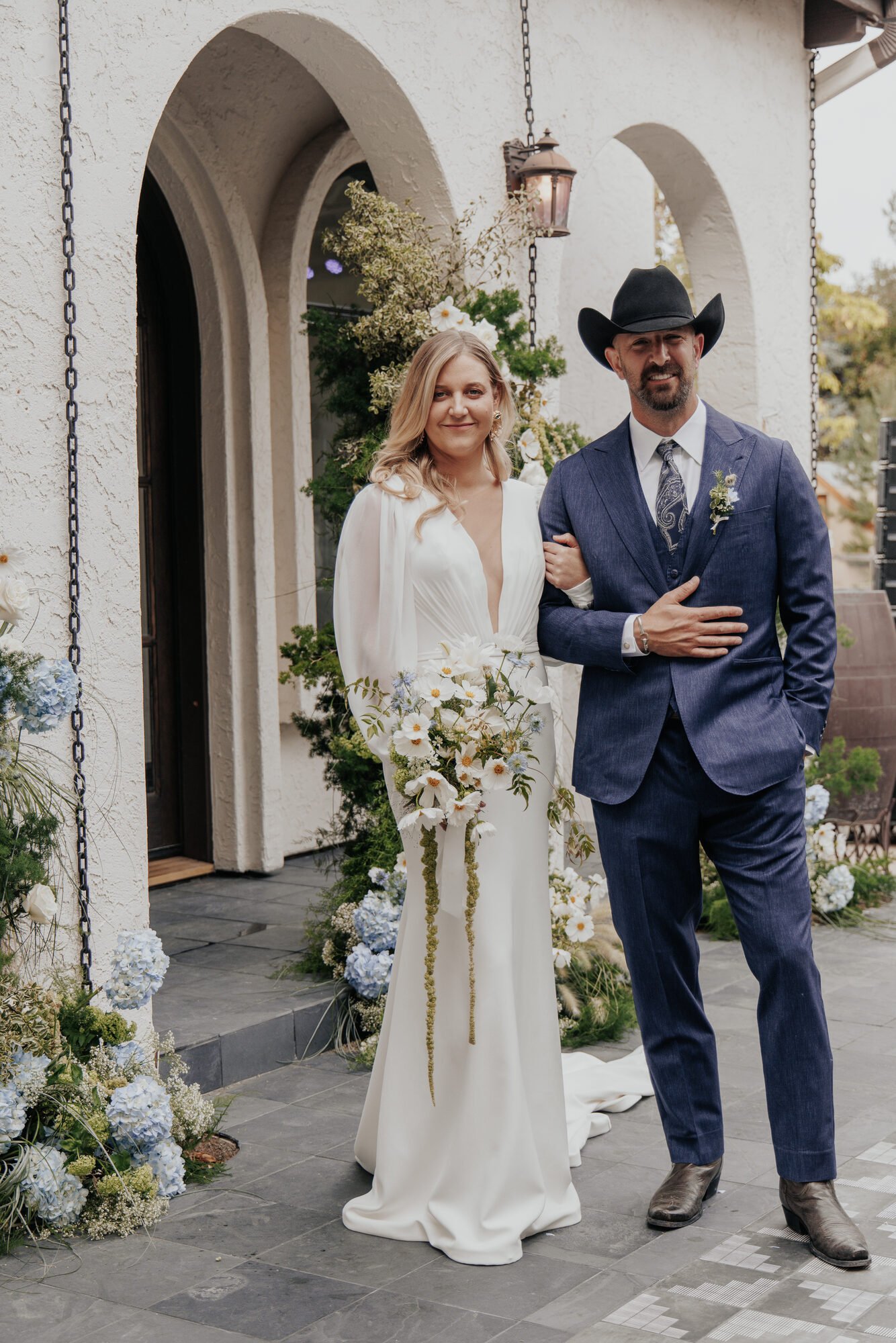 Buckstein wedding couple with the groom in a custom blue suit, cowboy hat, and boots