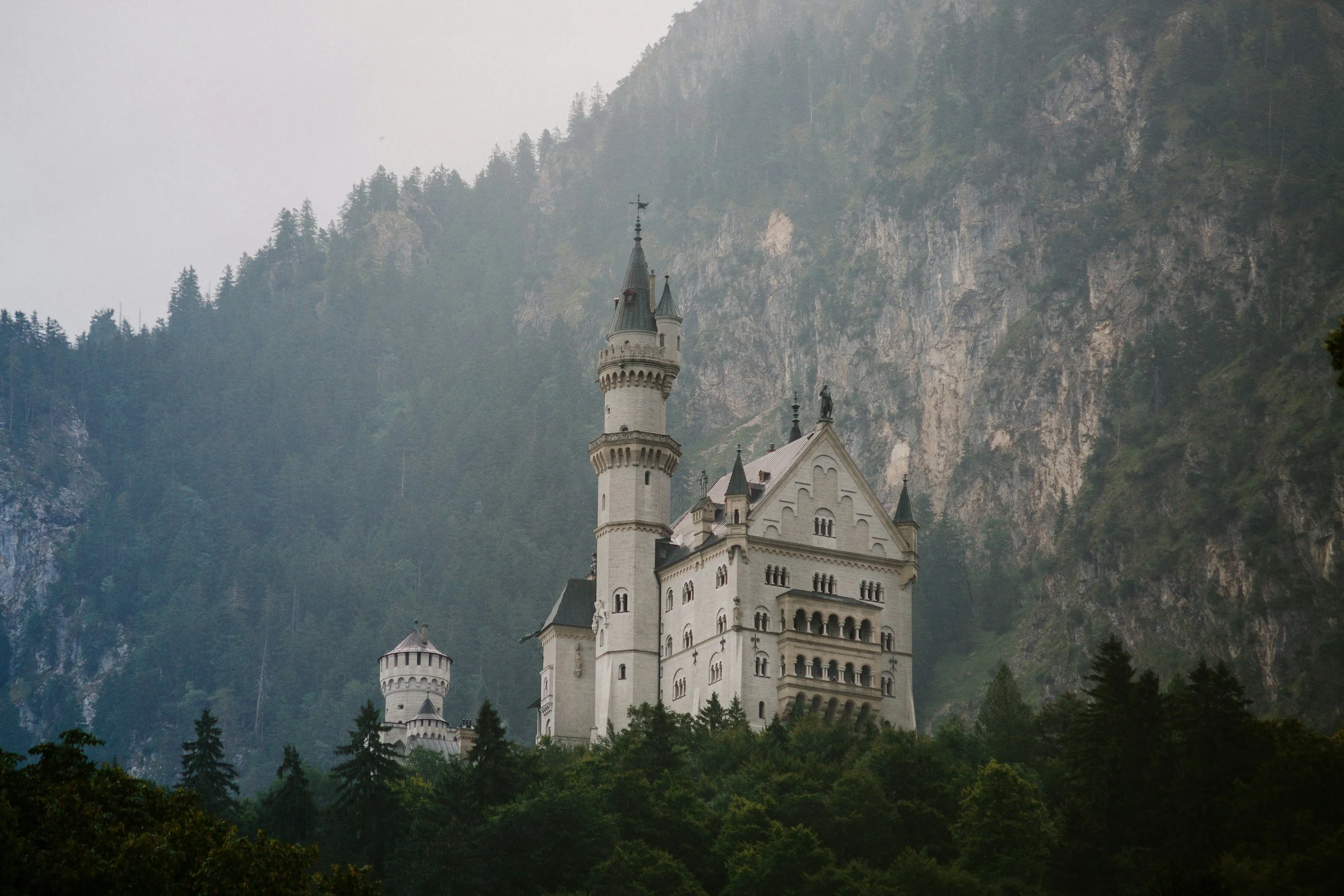 新天鵝堡全景視角，從遠處欣賞城堡與山林環繞的壯麗景色，是德國南部最經典的必訪景點之一。