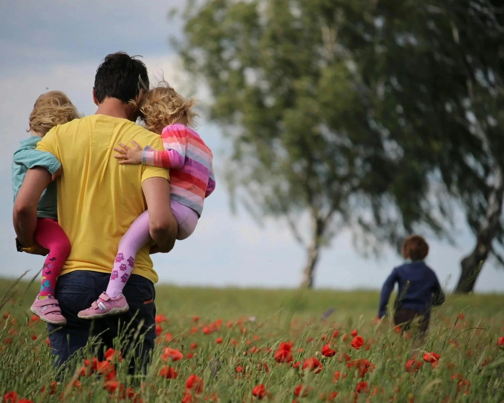 Parent carrying children outdoors in a field