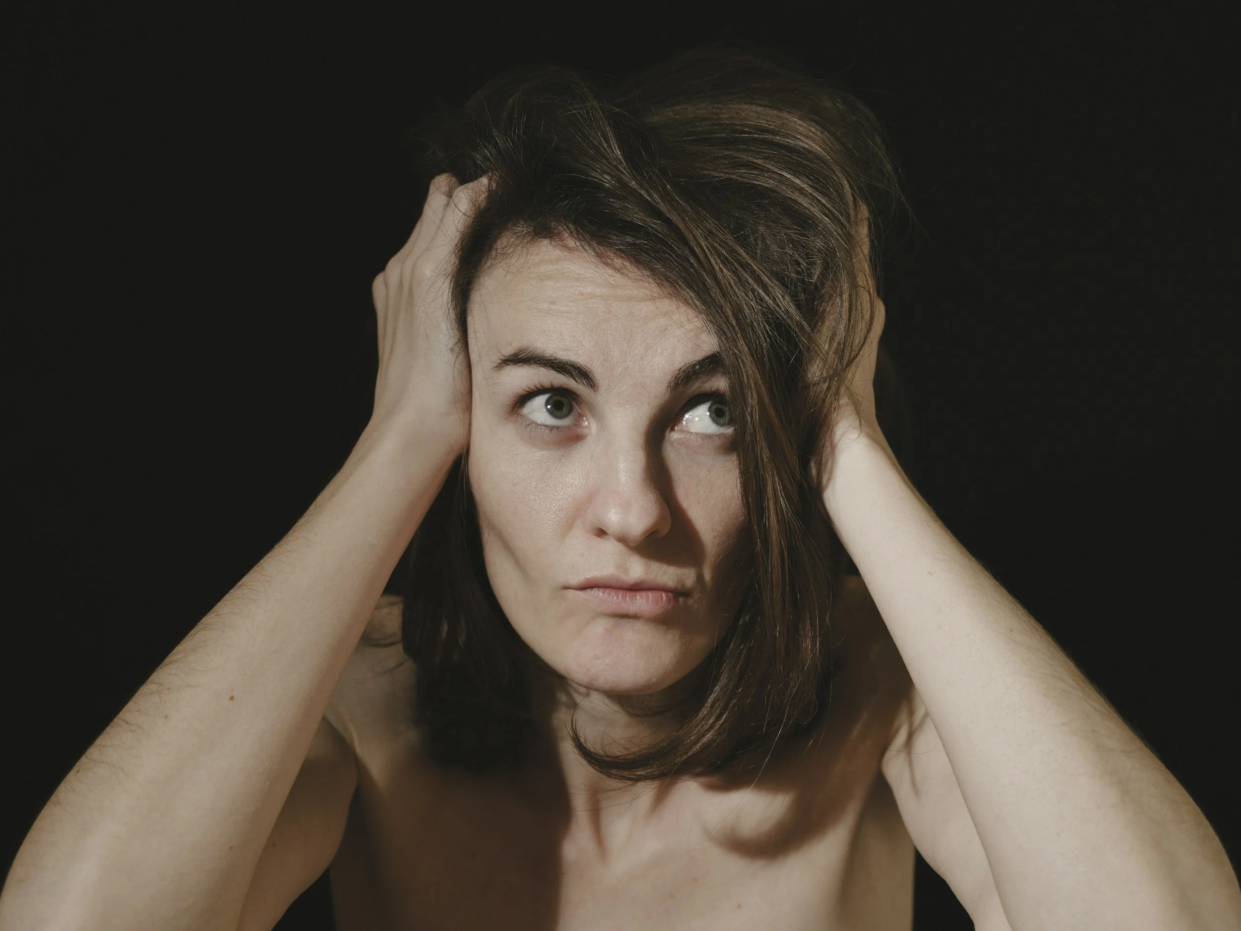 Woman holding her head, appearing overwhelmed and tense