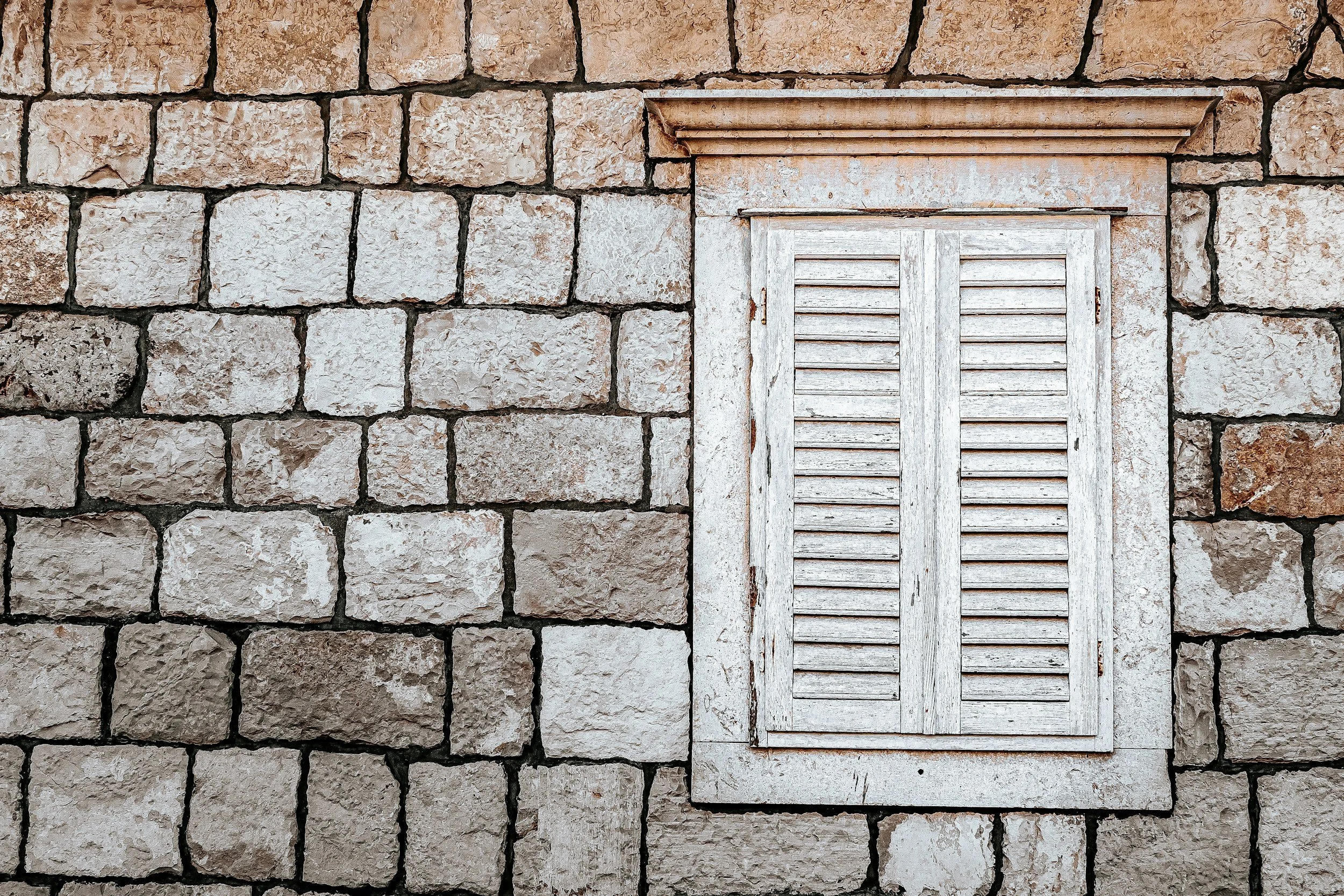 Closed window in a stone wall, representing emotional shutdown and silence