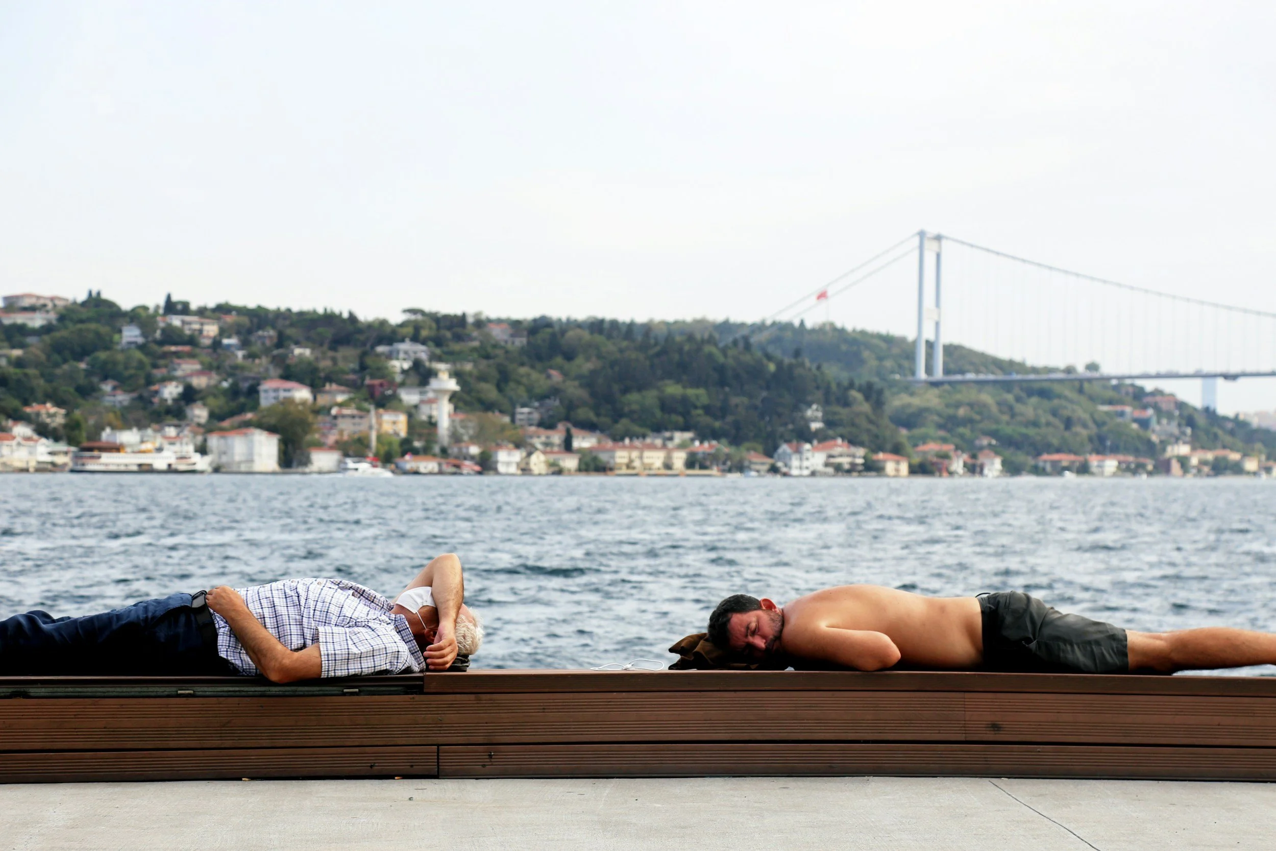 Two people lying apart on a wooden platform, representing emotional distance and repeating relationship patterns.
