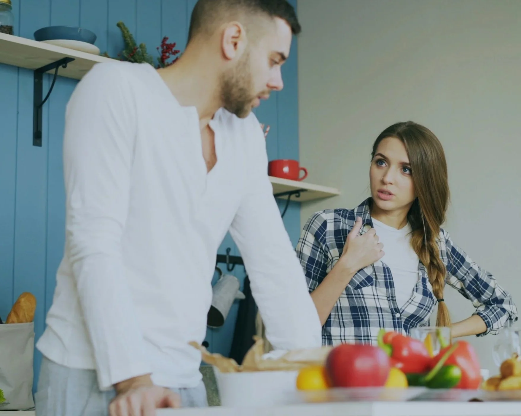 Couple arguing in a kitchen while standing apart emotionally.