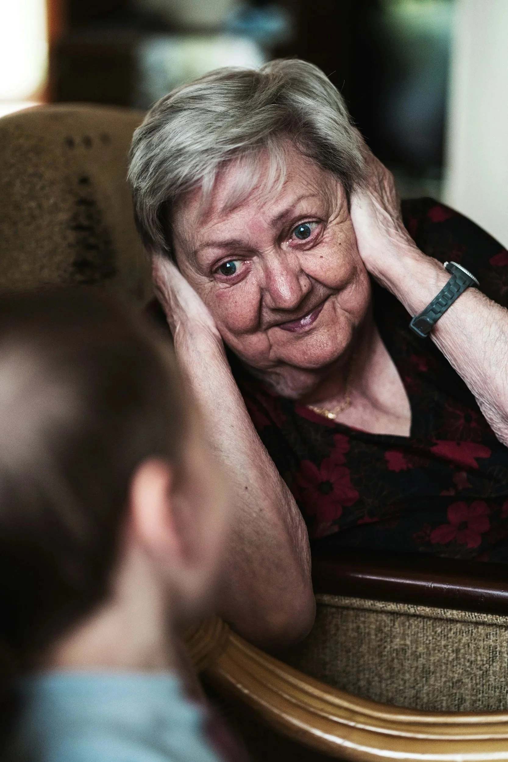Older woman covering her ears while a younger woman speaks to her