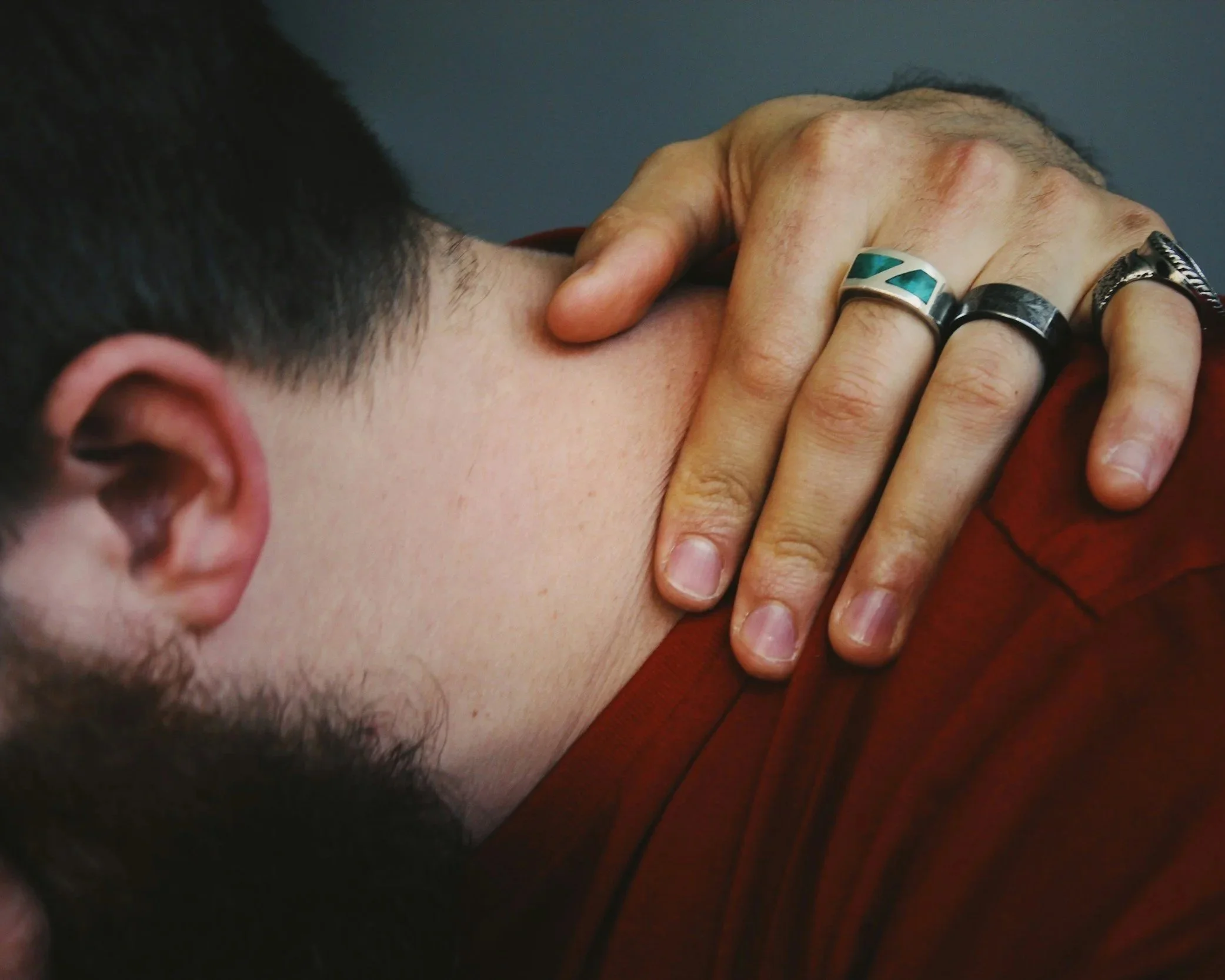 Person leaning forward with hand on neck appearing emotionally distressed and overwhelmed.