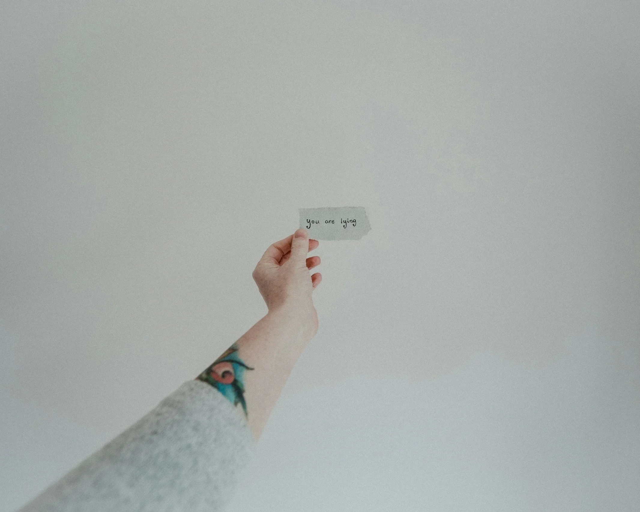 Hand holding a small card, representing self-deception and holding onto beliefs in relationships