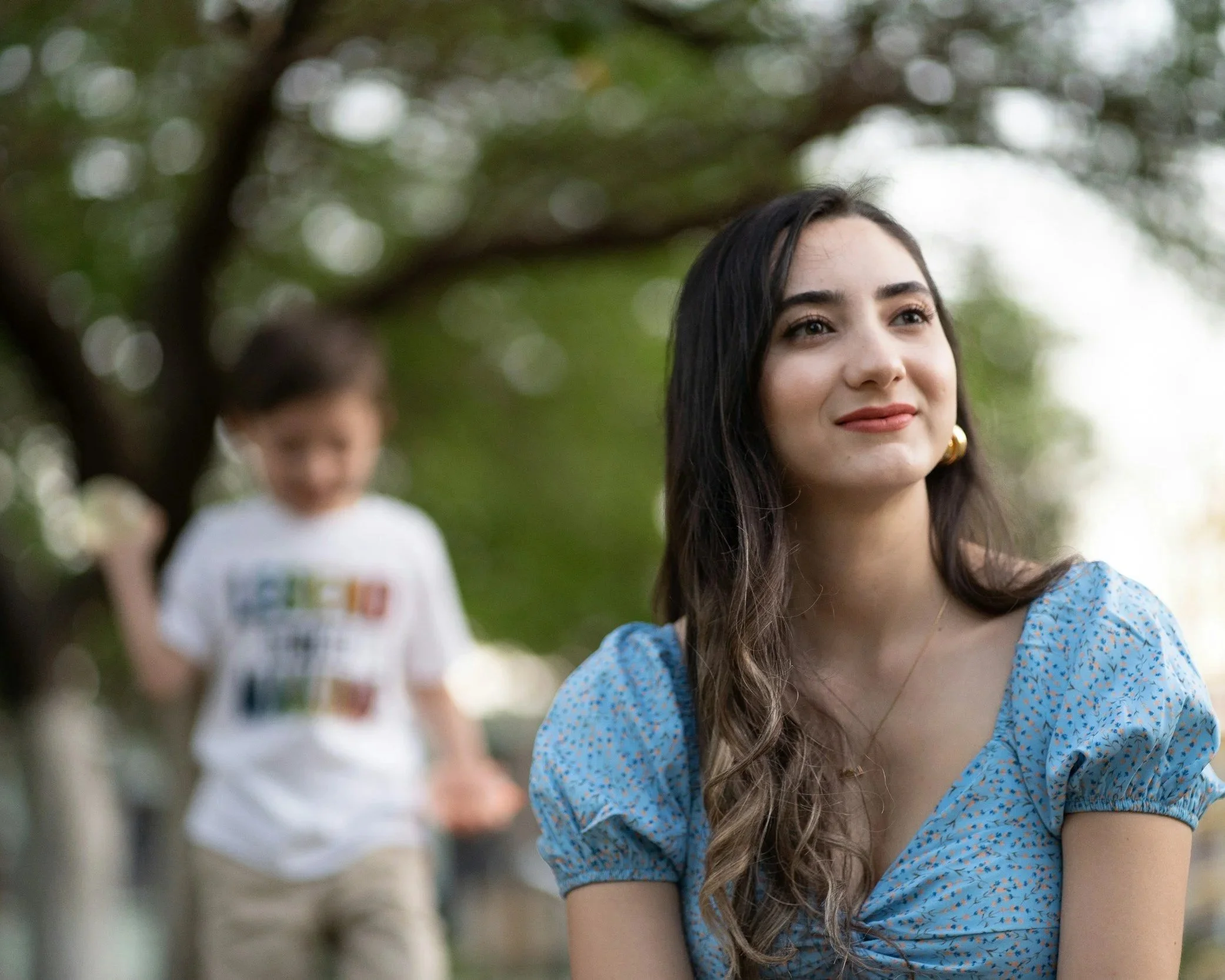 woman reflecting while child plays in background, representing emotional distance in parenting relationships