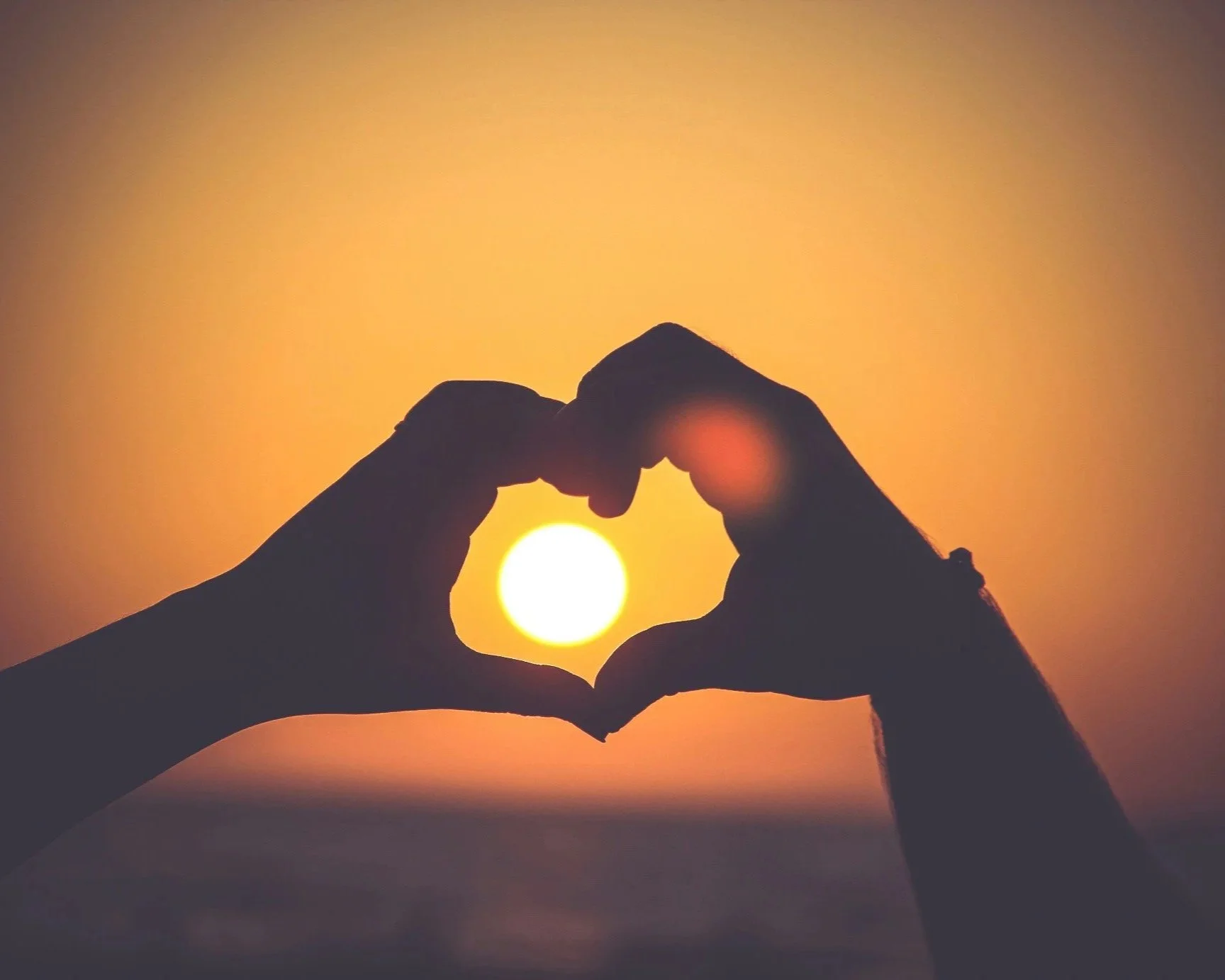 Hands forming a heart shape around the sun, representing rebuilding trust and connection