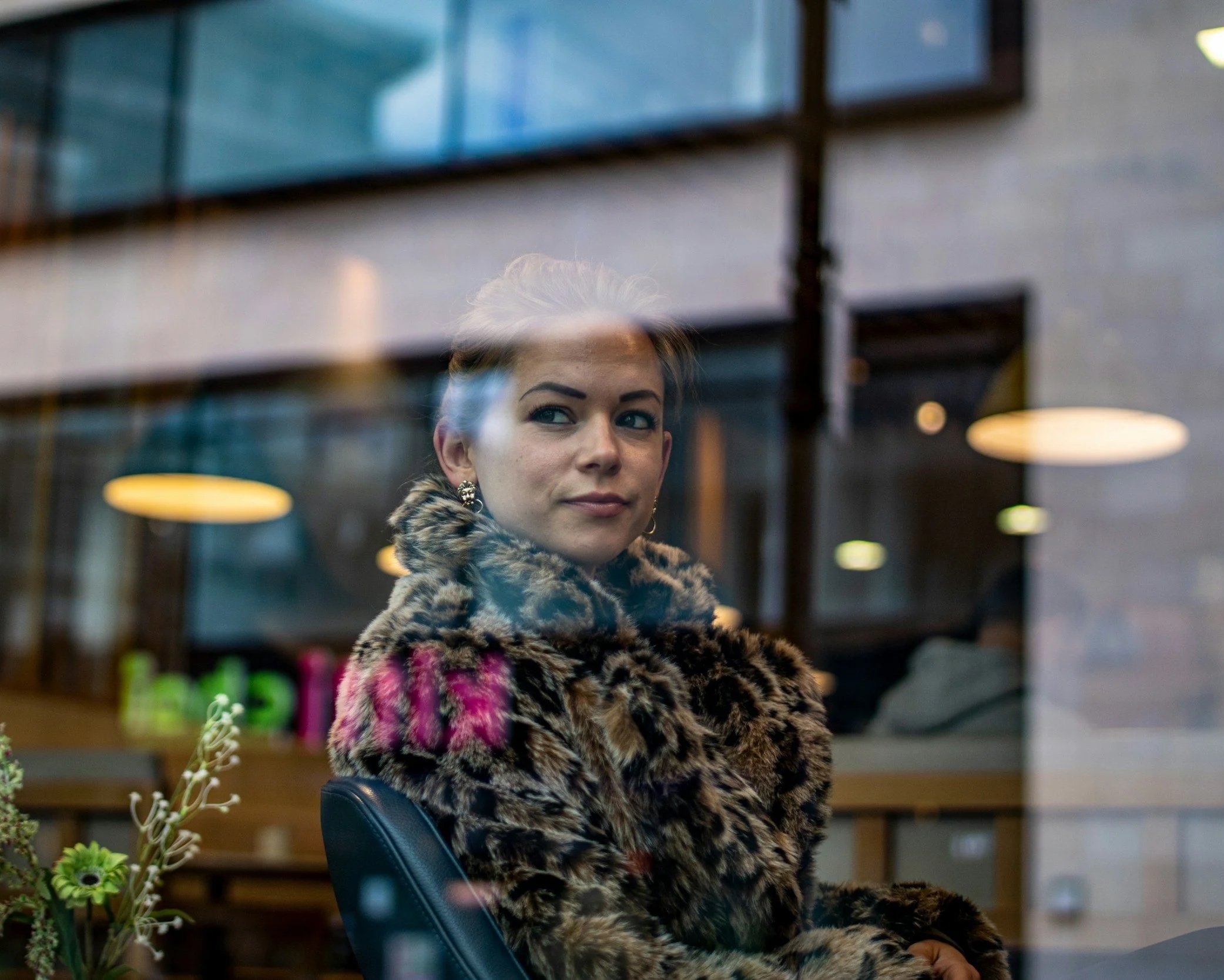 Woman looking through a rain-covered window appearing emotionally isolated.