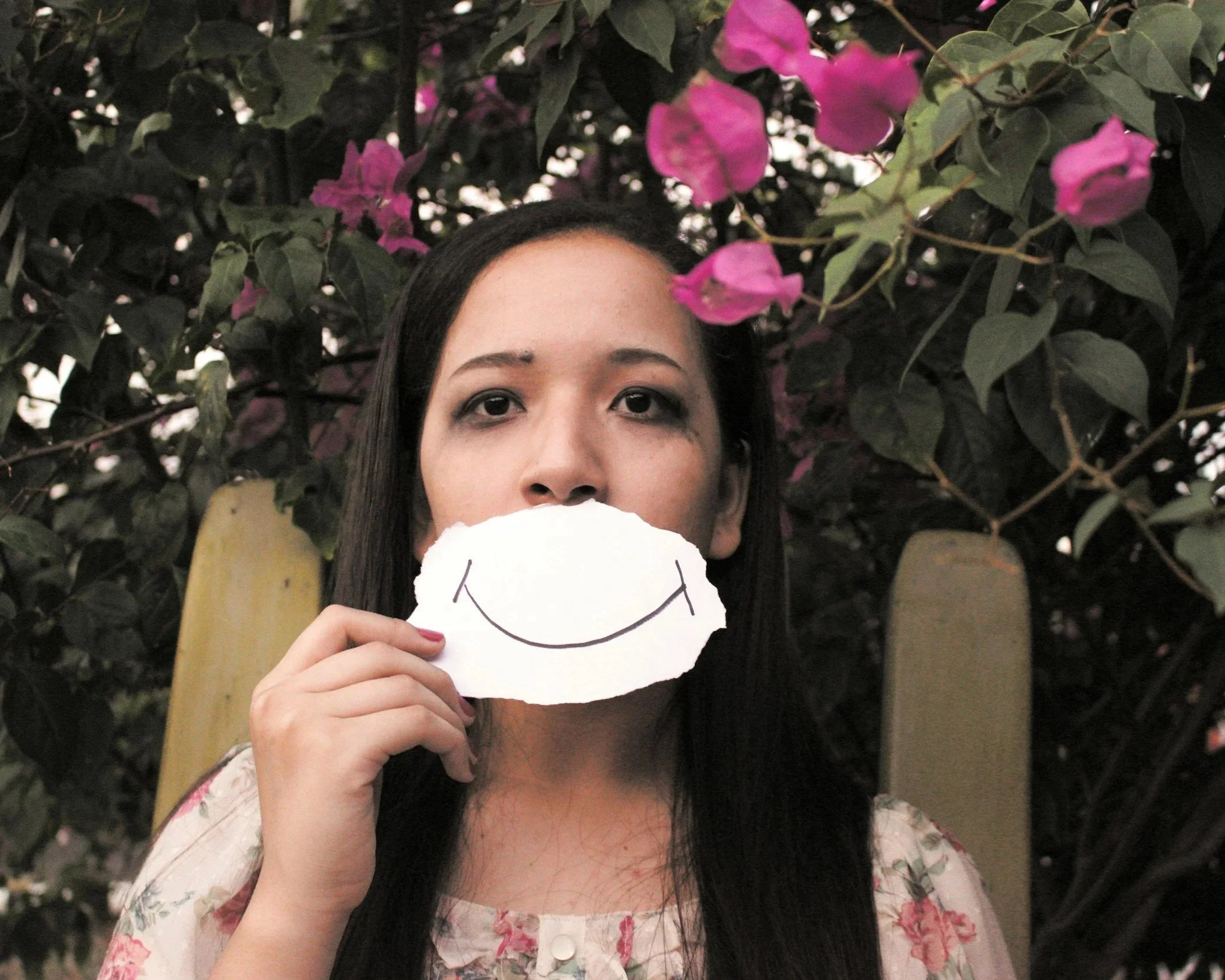 Woman holding a mask representing people-pleasing and hiding true feelings