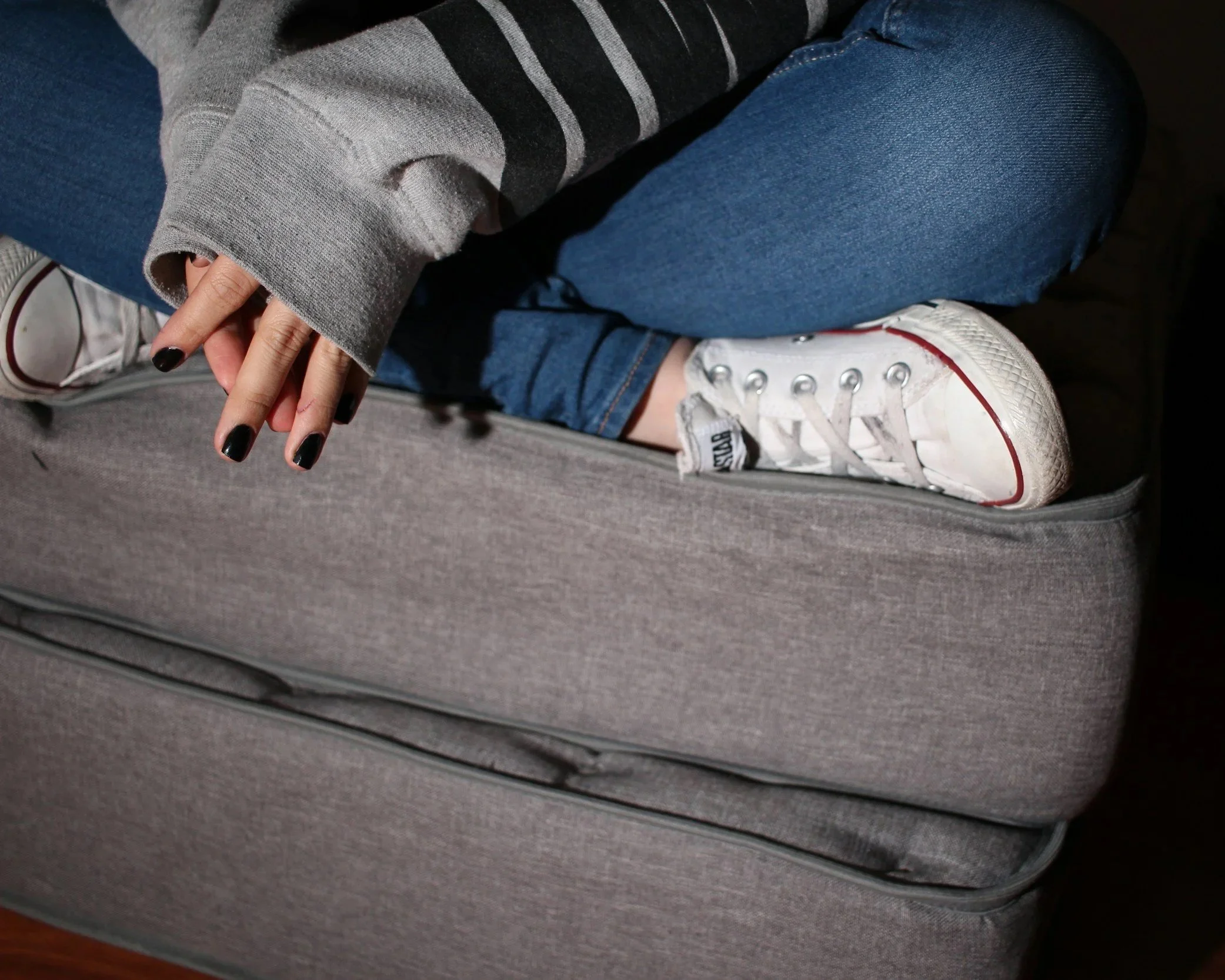 Person curled up on a couch appearing withdrawn and emotionally distressed.