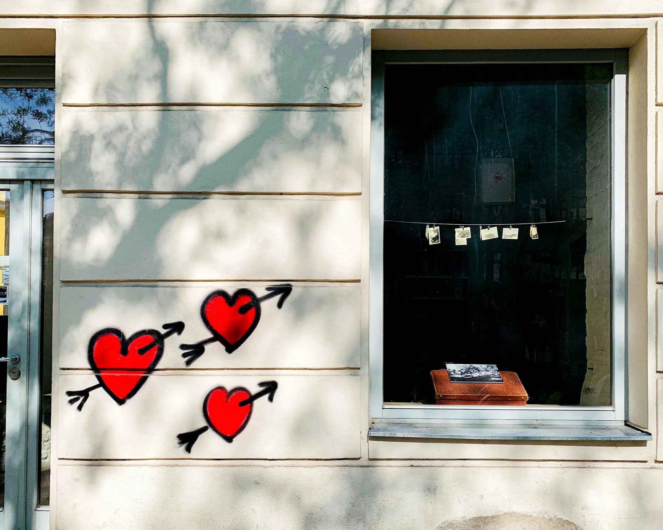 Small hearts drawn on a wall near a window, representing longing and romantic fixation