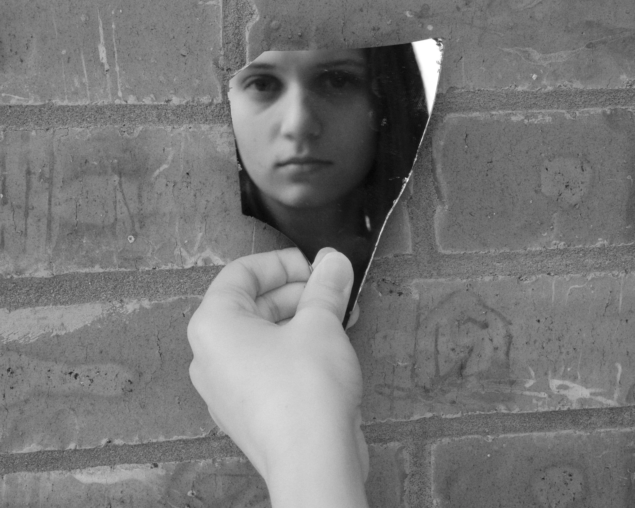 Person holding a mirror reflecting part of their face