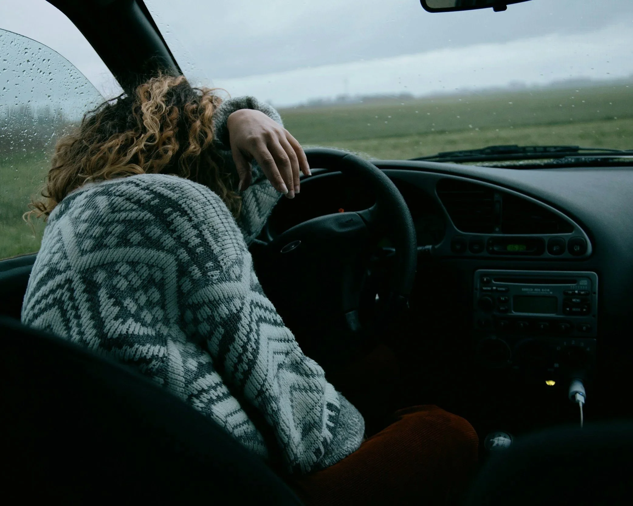 Woman sitting alone in a car representing emotional exhaustion and the burden of being the strong one