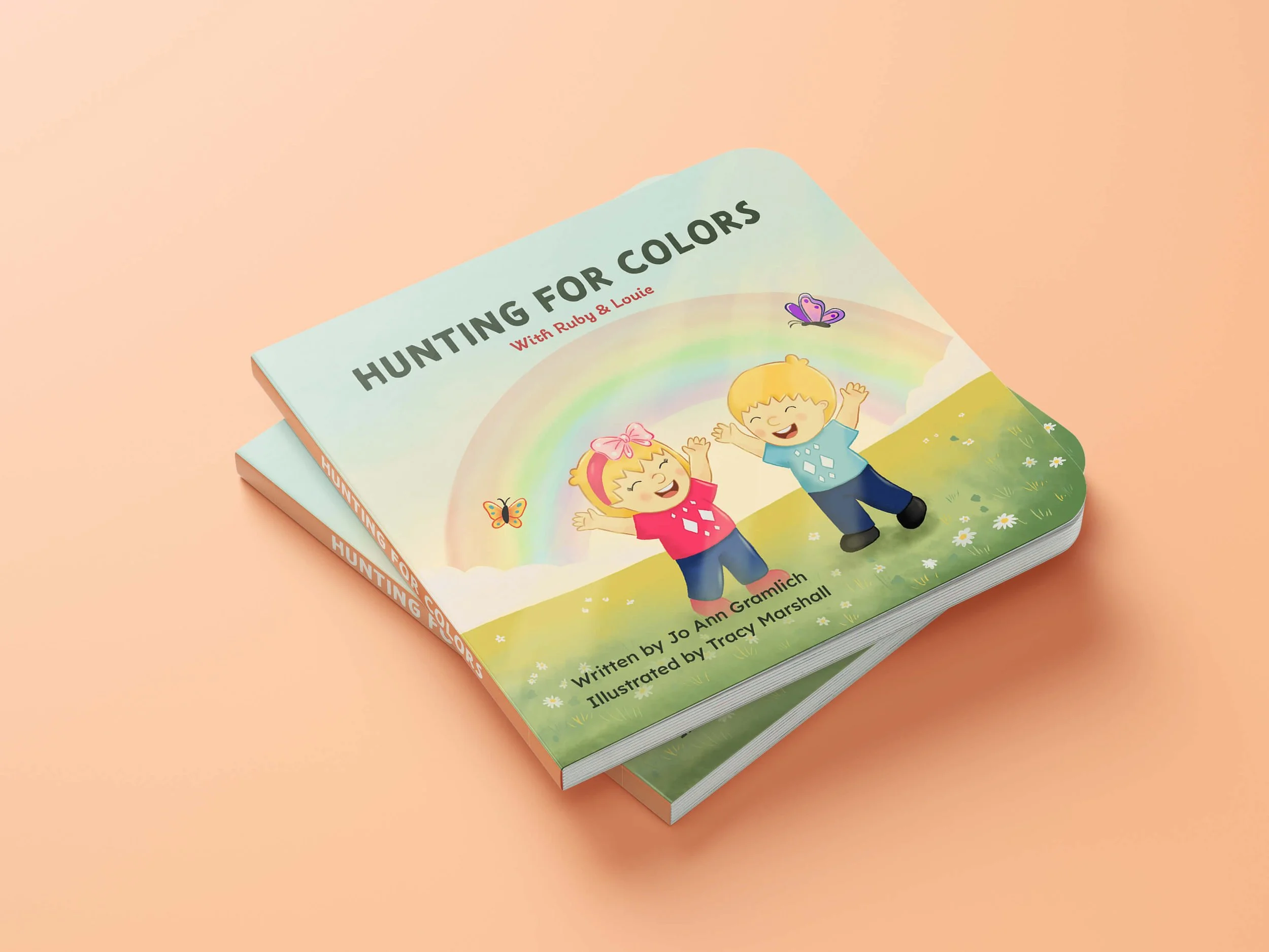 Mockup of the children’s book Hunting for Colors with Ruby and Louie standing under a rainbow.